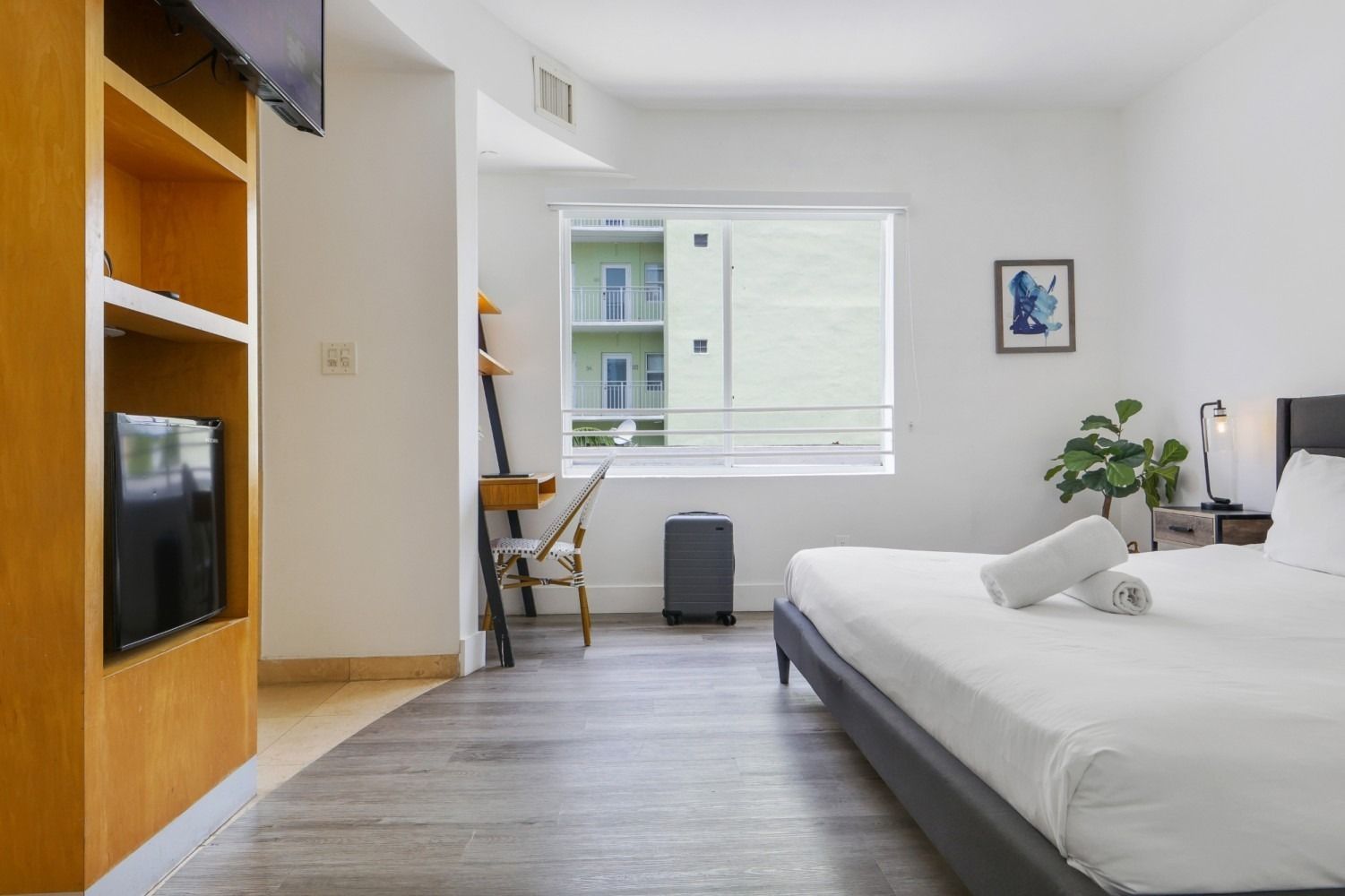 Bedroom with bed, desk, window, and built-in shelving unit.