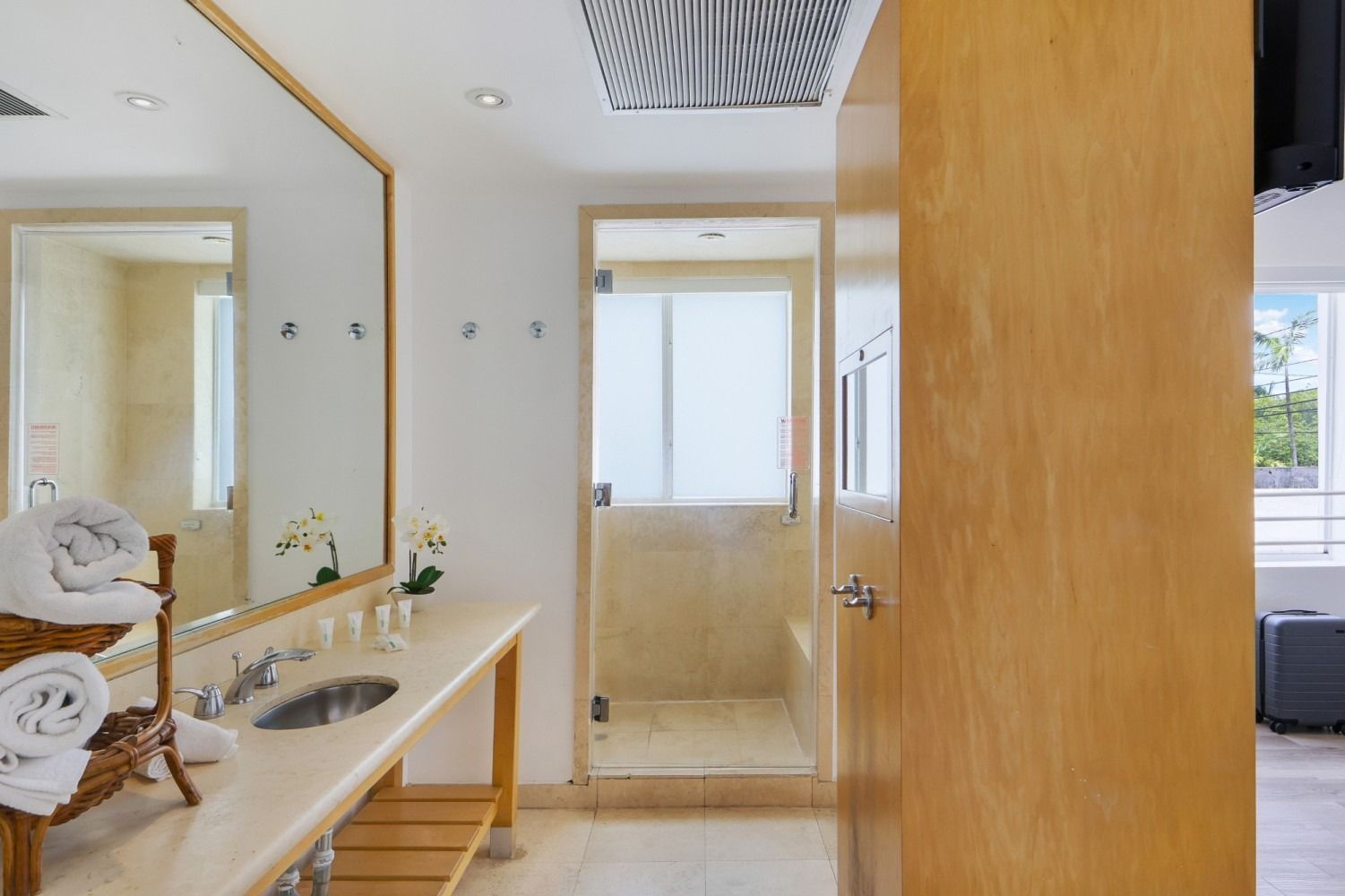 Bathroom with marble countertop, double sinks, large mirror, and glass shower.