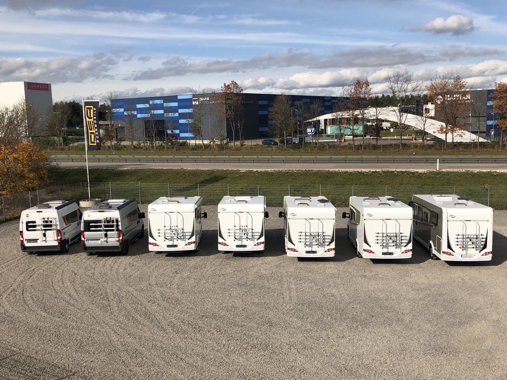 Auf einem Parkplatz steht eine Reihe Wohnmobile.