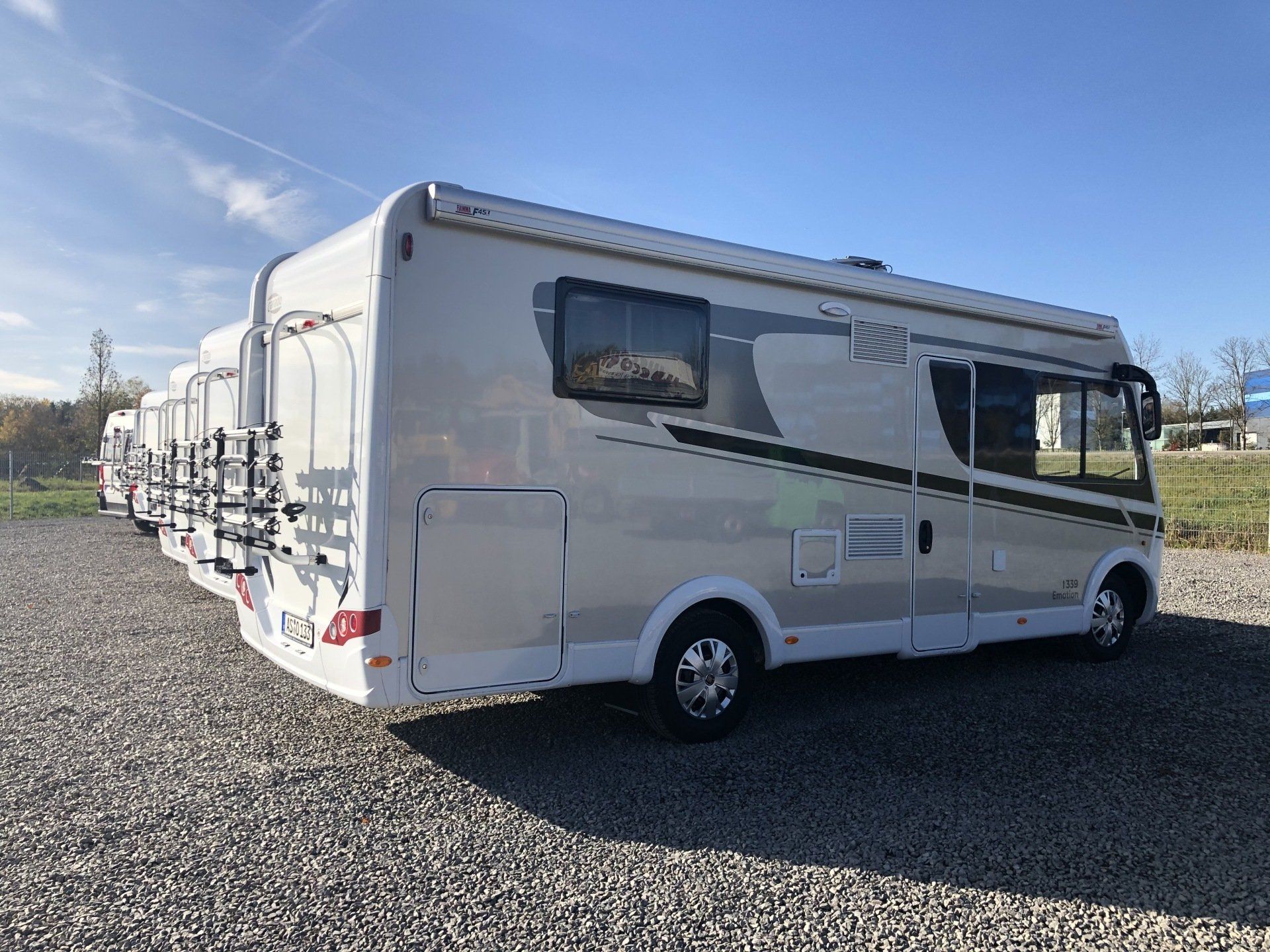 Ein weißes Wohnmobil ist auf einem Schotterplatz geparkt.