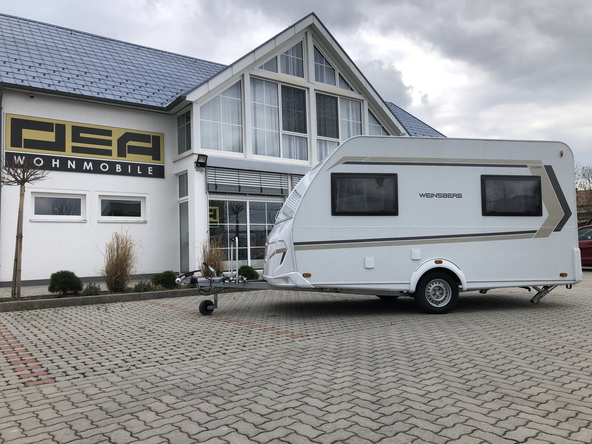 A white trailer is parked in front of a building.