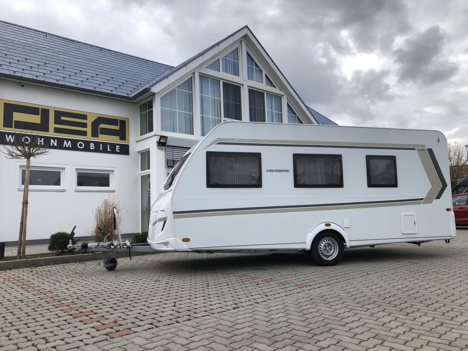 A white trailer is parked in front of a building.