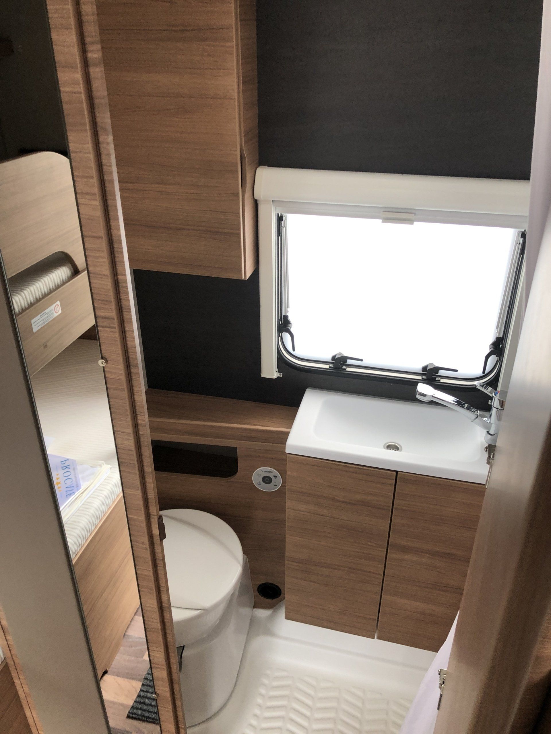 A bathroom with a toilet a sink and a window