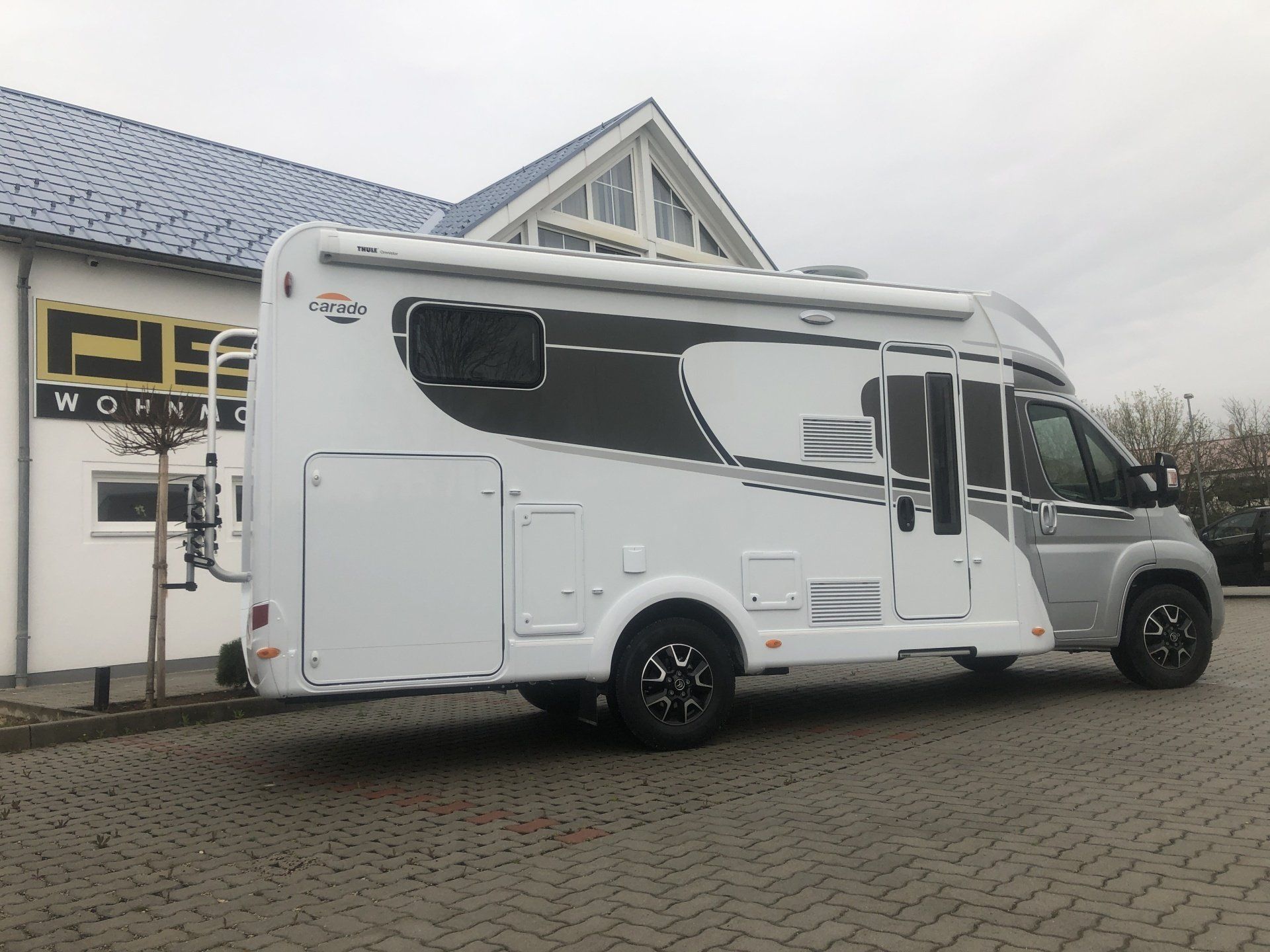 A white rv is parked in front of a building.