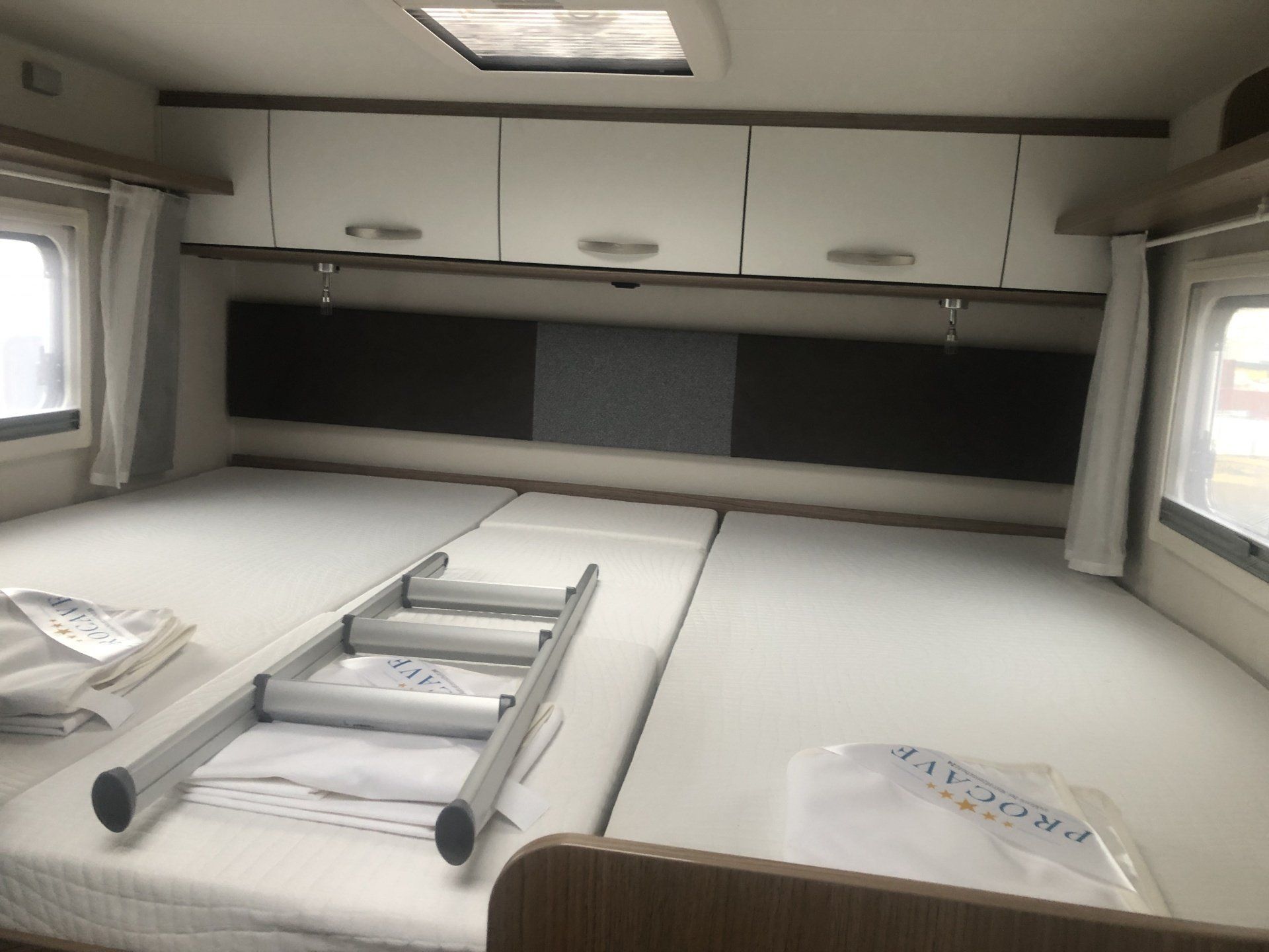 A ladder is sitting on top of a bed in a camper.