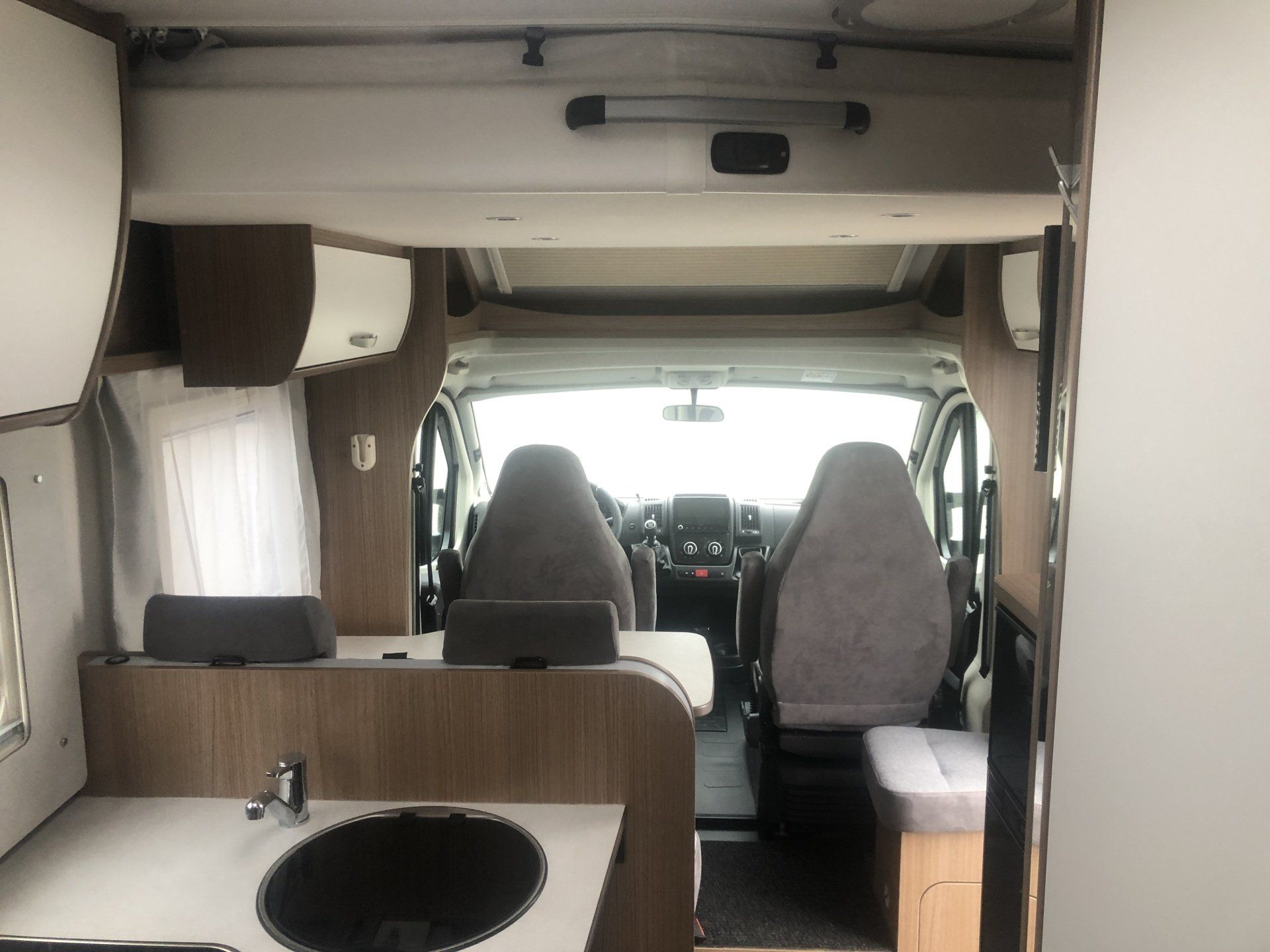 The inside of a camper van with a sink and chairs.