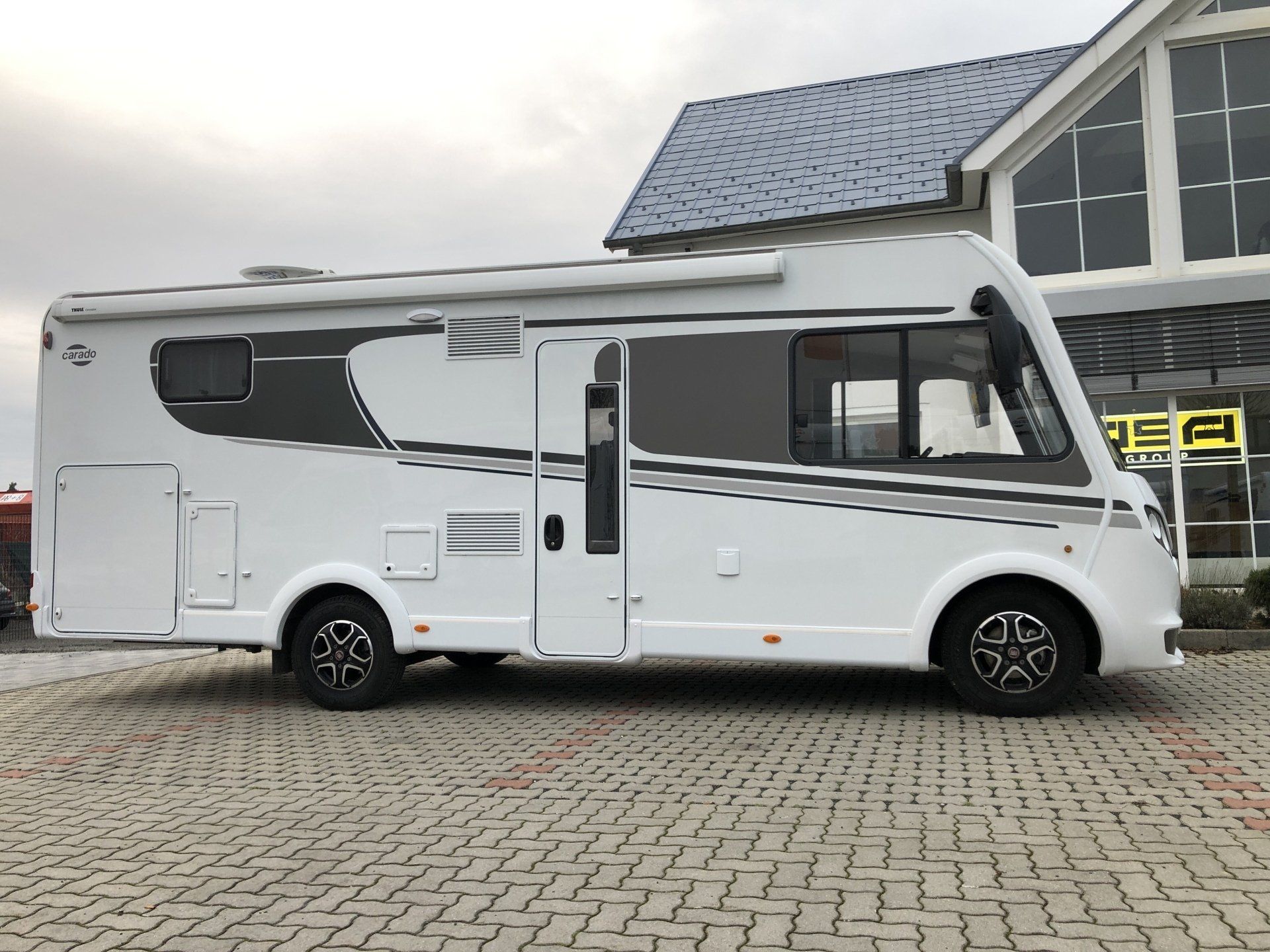 Ein weißes Wohnmobil ist vor einem Gebäude geparkt.