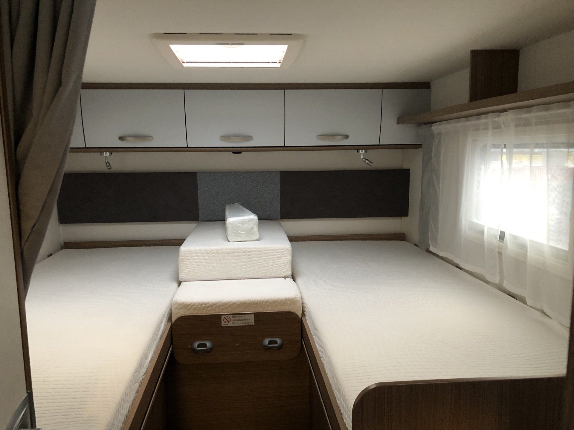 Der Innenraum eines Wohnmobils mit zwei Betten und einem Fenster.