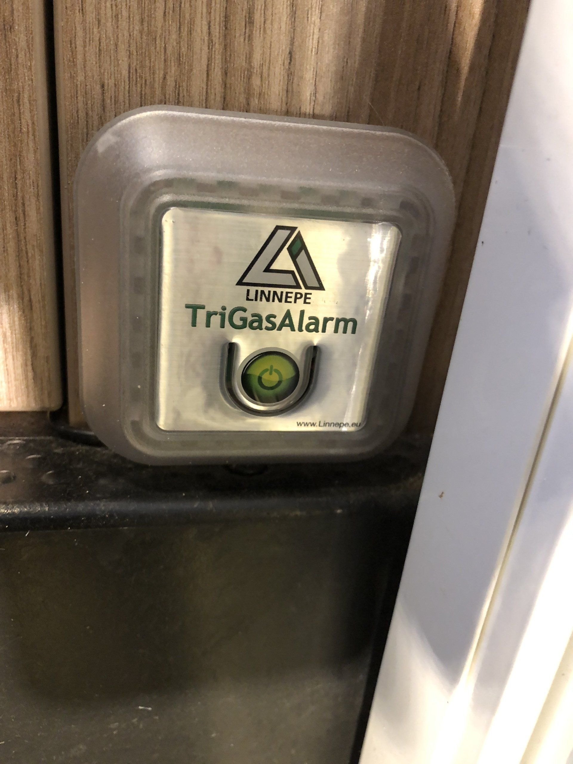 A trigas alarm is sitting on a wooden wall next to a door.