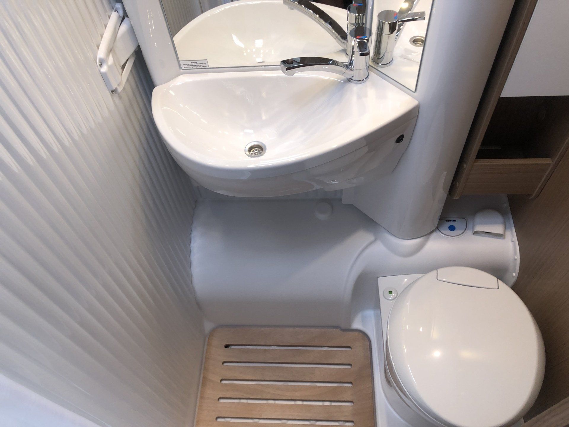 A bathroom with a toilet , sink and mirror.
