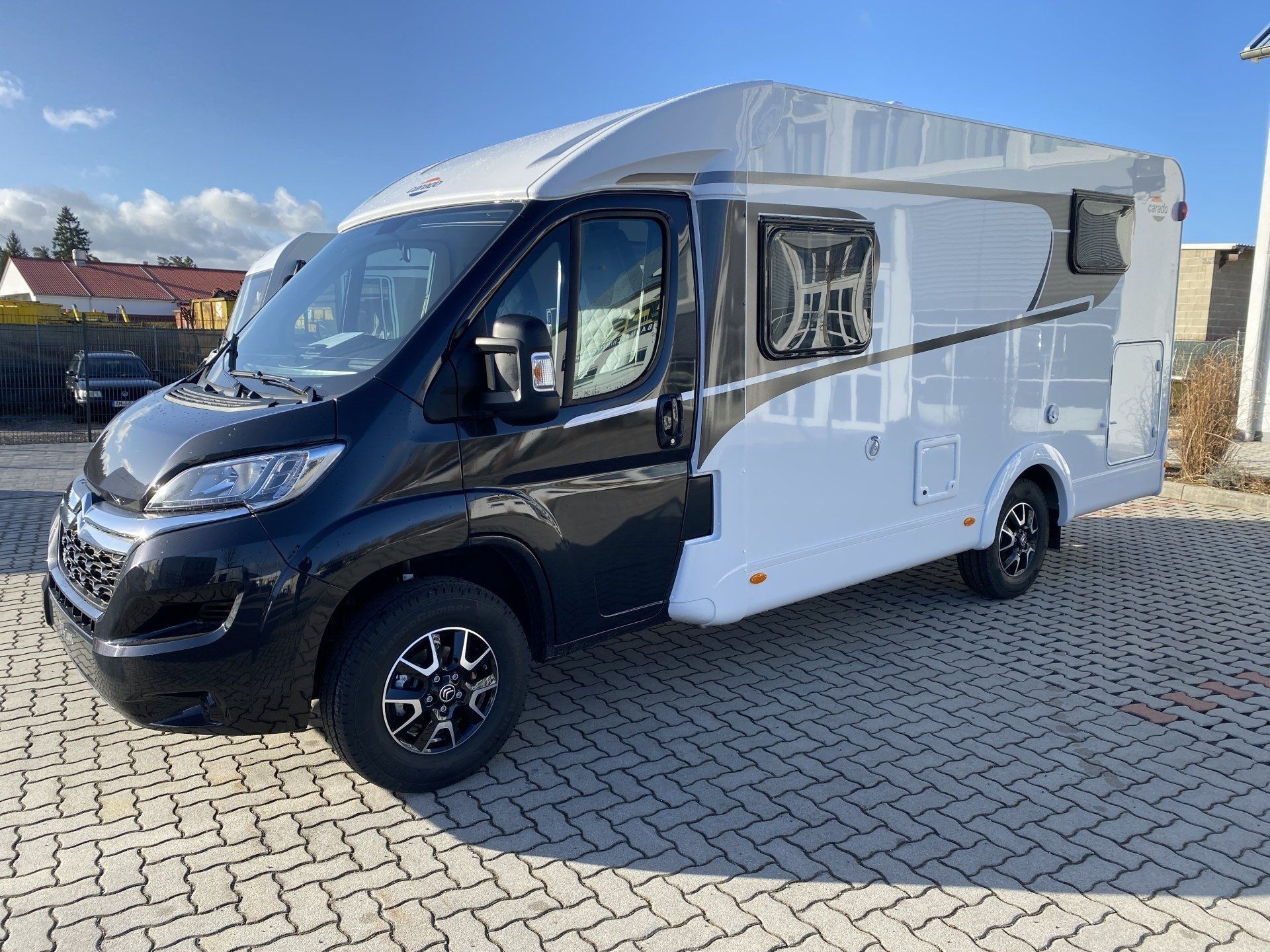 A black and white camper van is parked on a brick driveway.