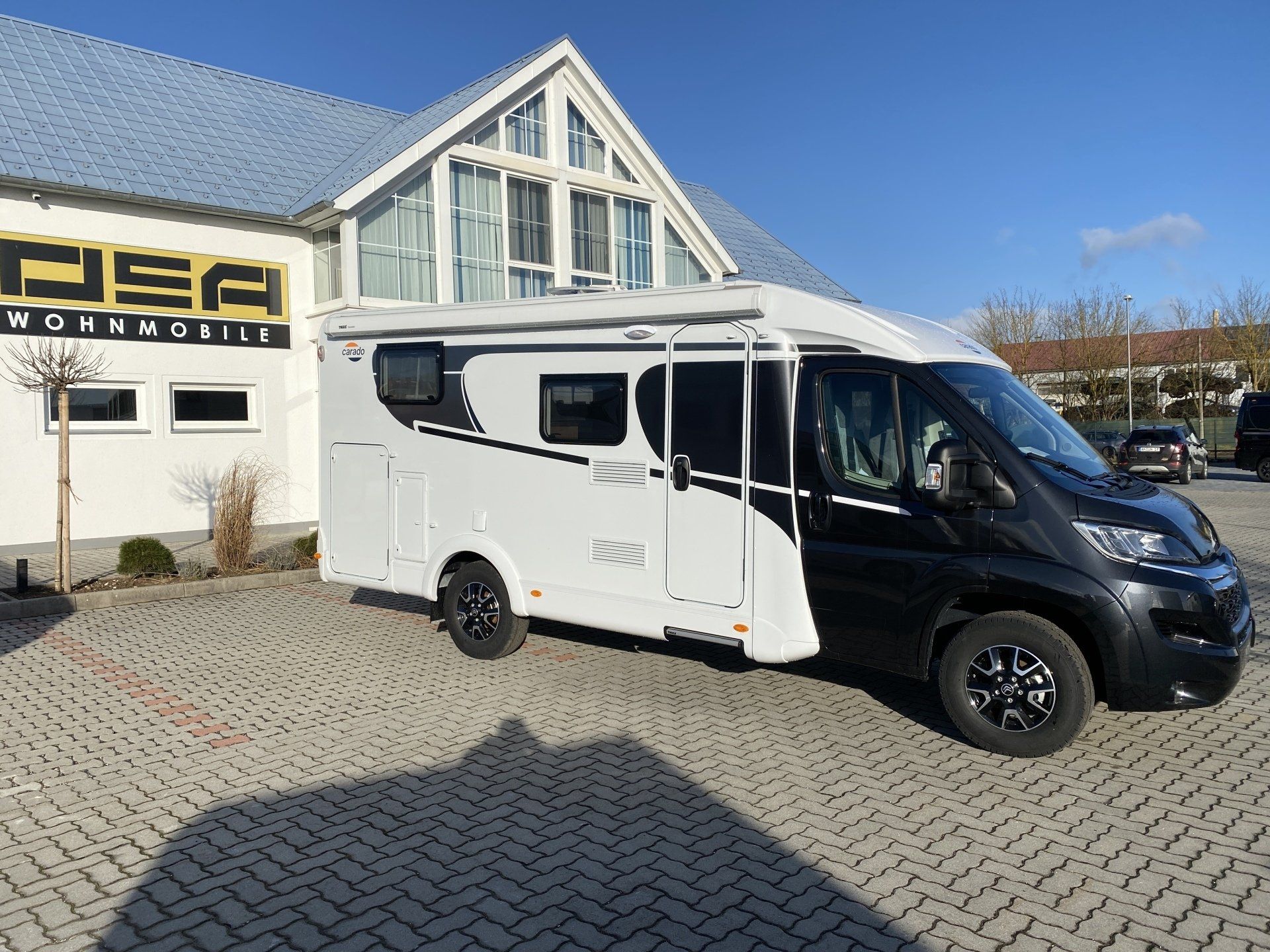 A black and white rv is parked in front of a building.