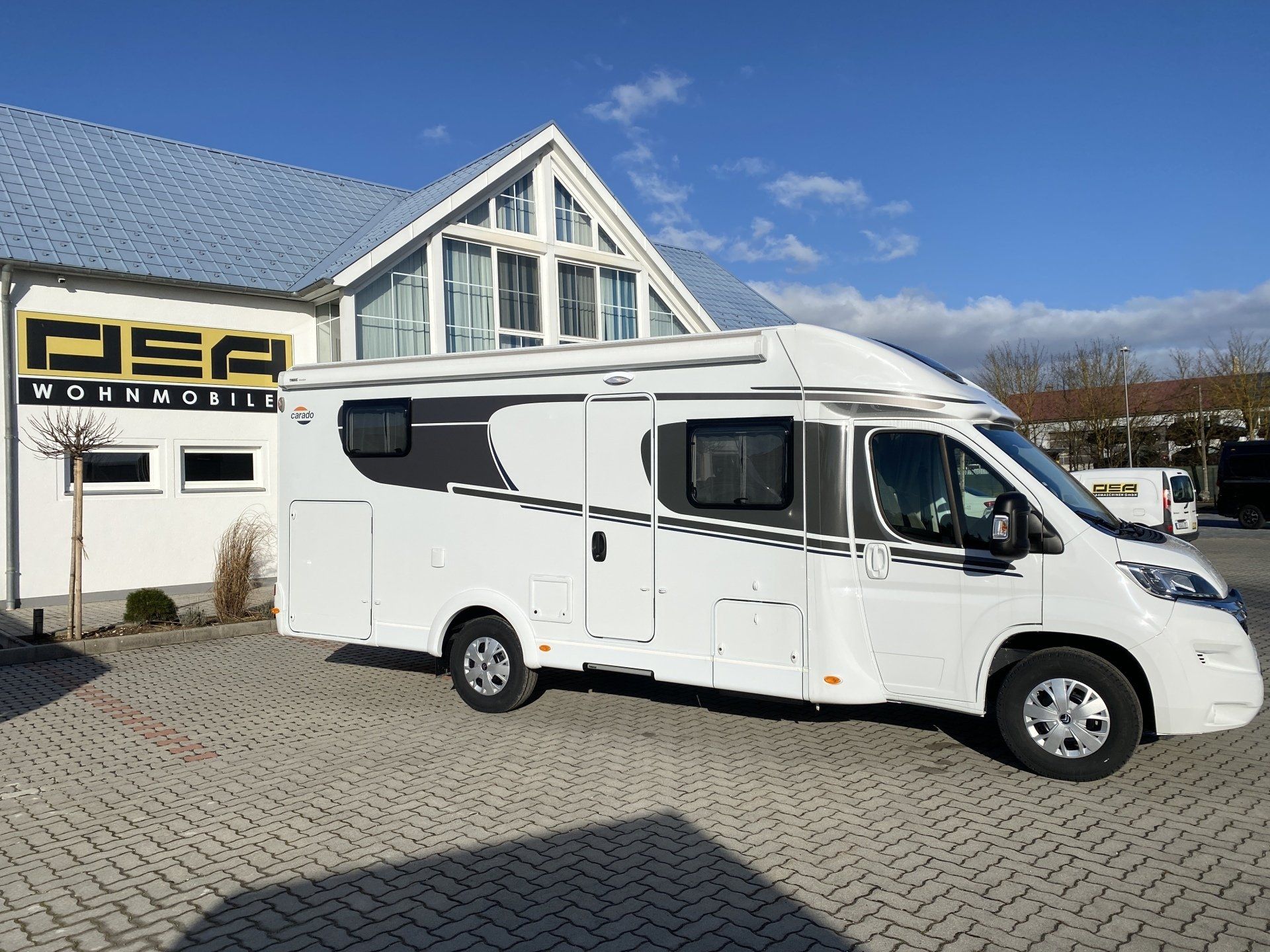 A white rv is parked in front of a building.