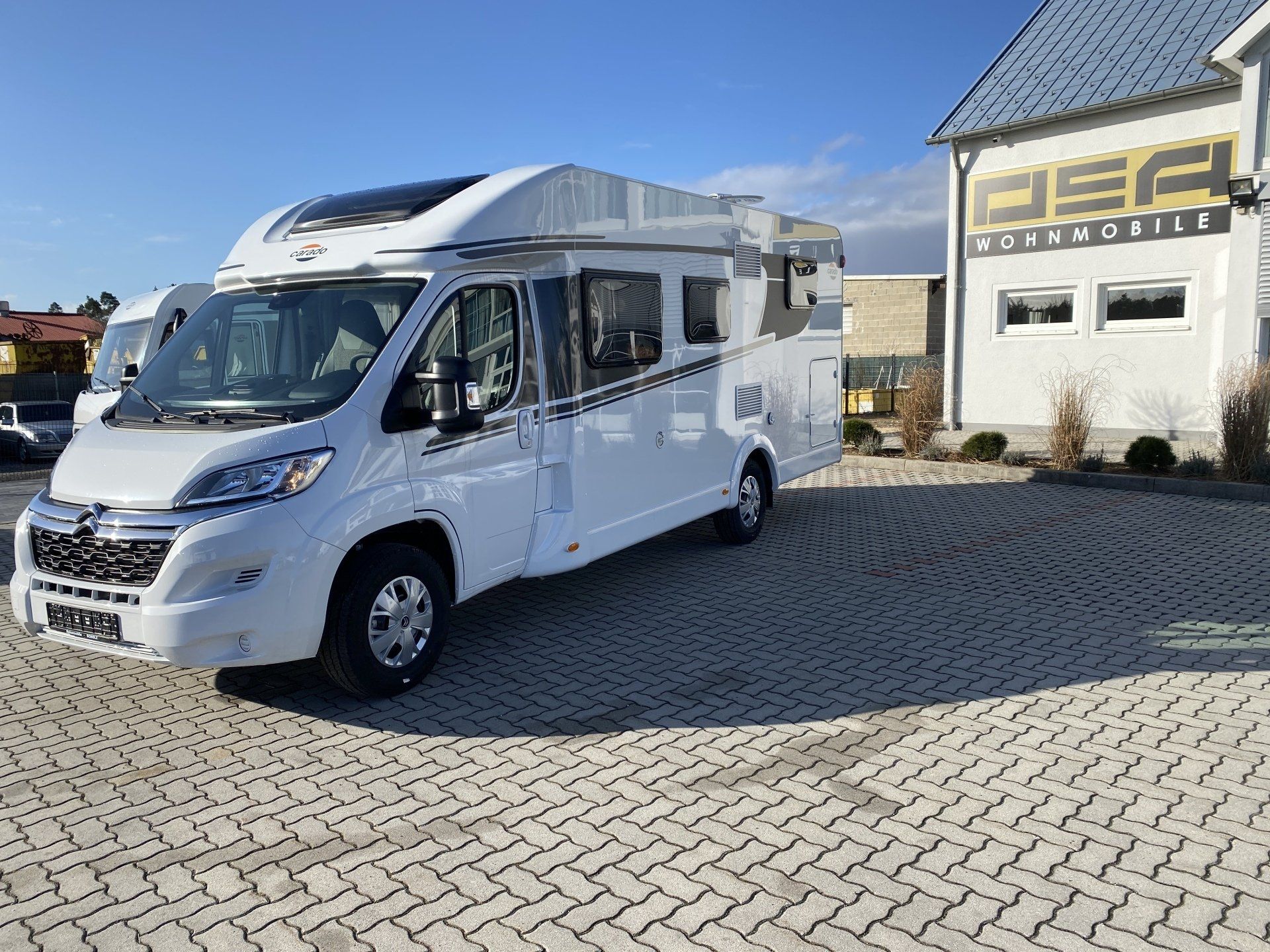 A white rv is parked in a parking lot in front of a building.