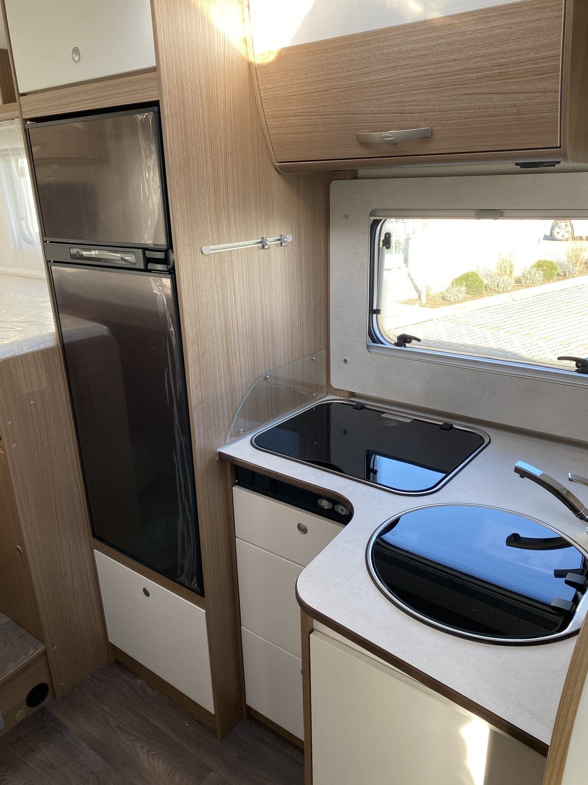 A kitchen in a camper with a sink , stove and refrigerator.