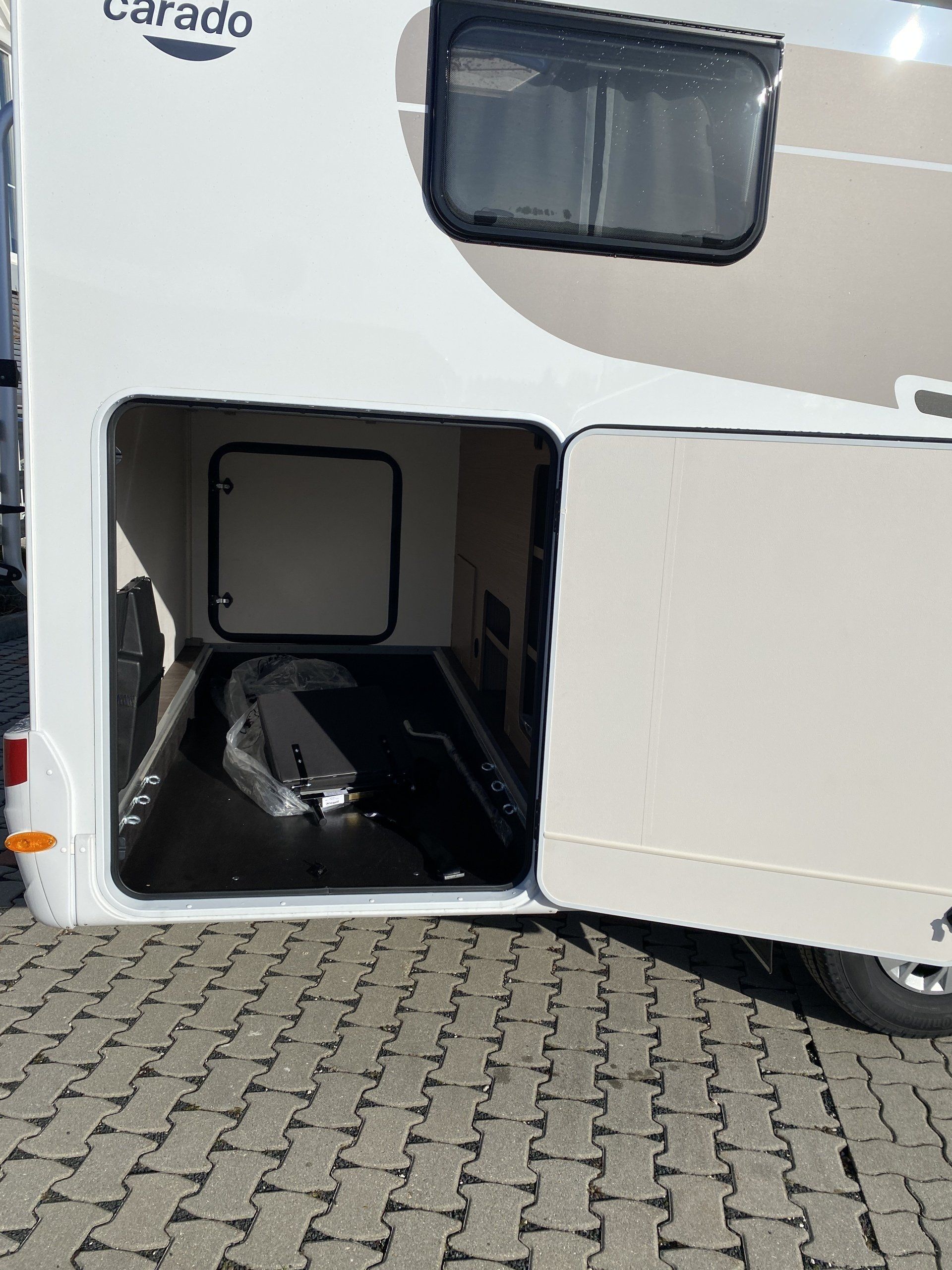 A white rv is parked on a brick sidewalk with the door open.
