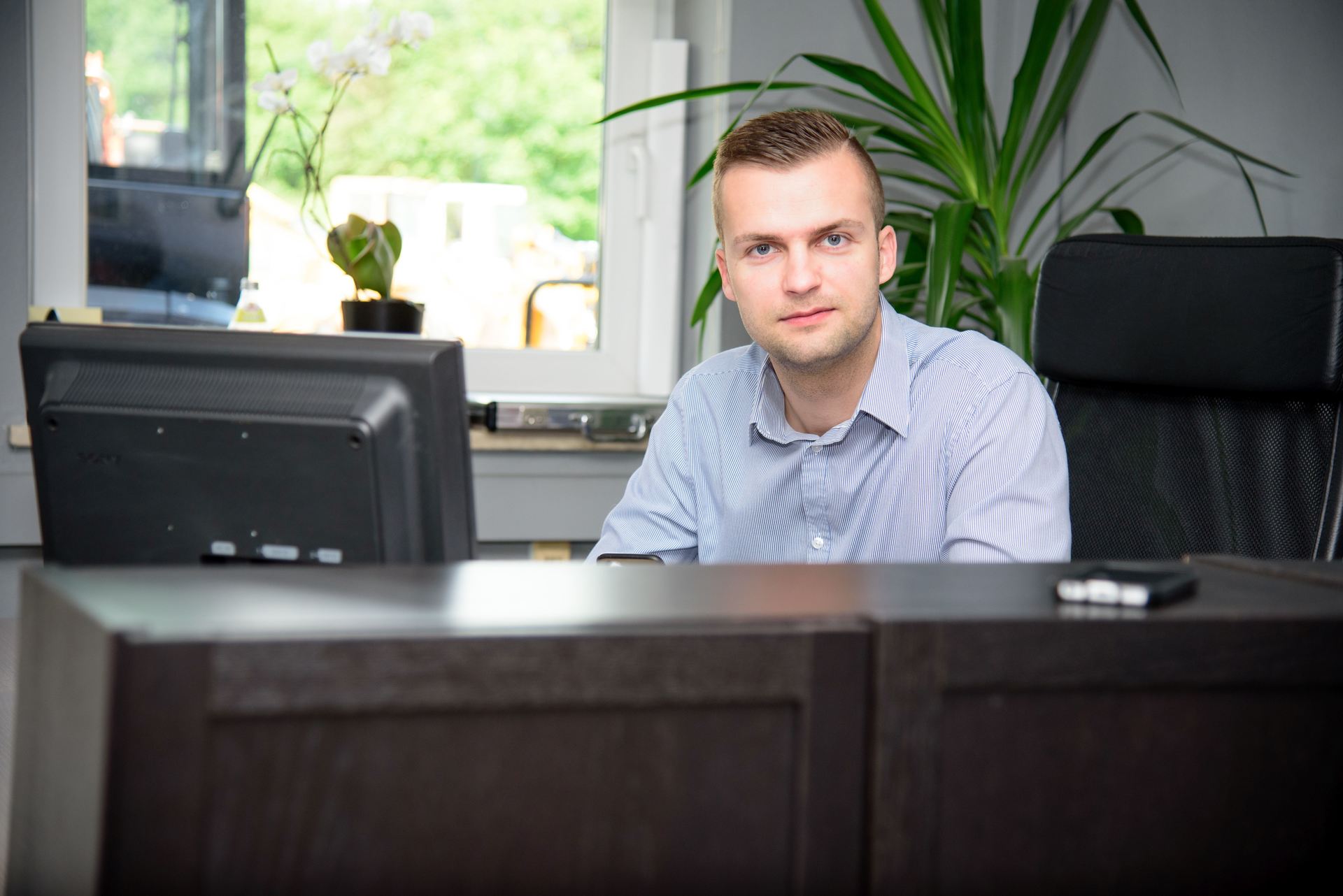 Ein Mann sitzt an einem Schreibtisch vor einem Computermonitor.