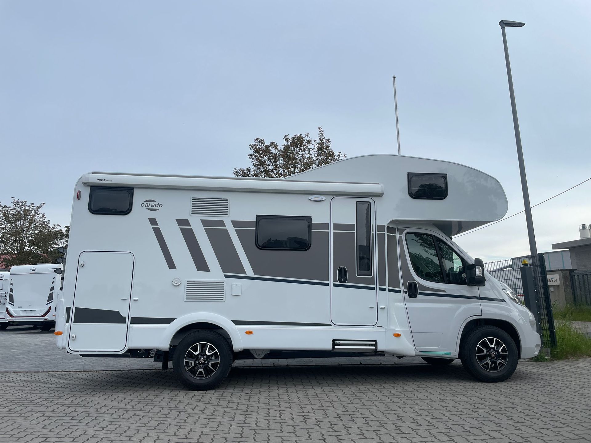 Ein weißes Wohnmobil steht auf einem Parkplatz neben einer Straßenlaterne.