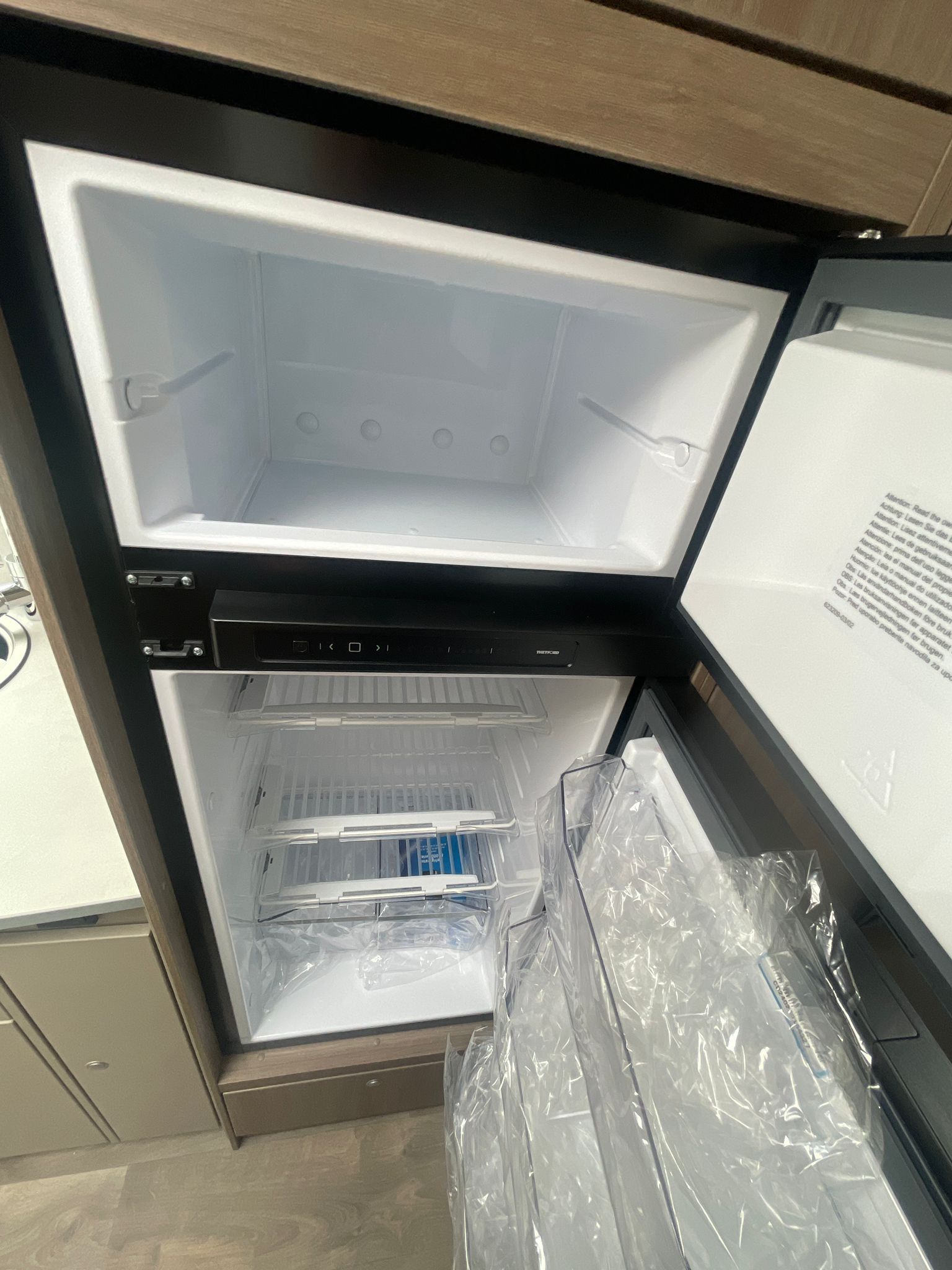 Ein leerer Kühlschrank mit offener Tür in einer Küche.