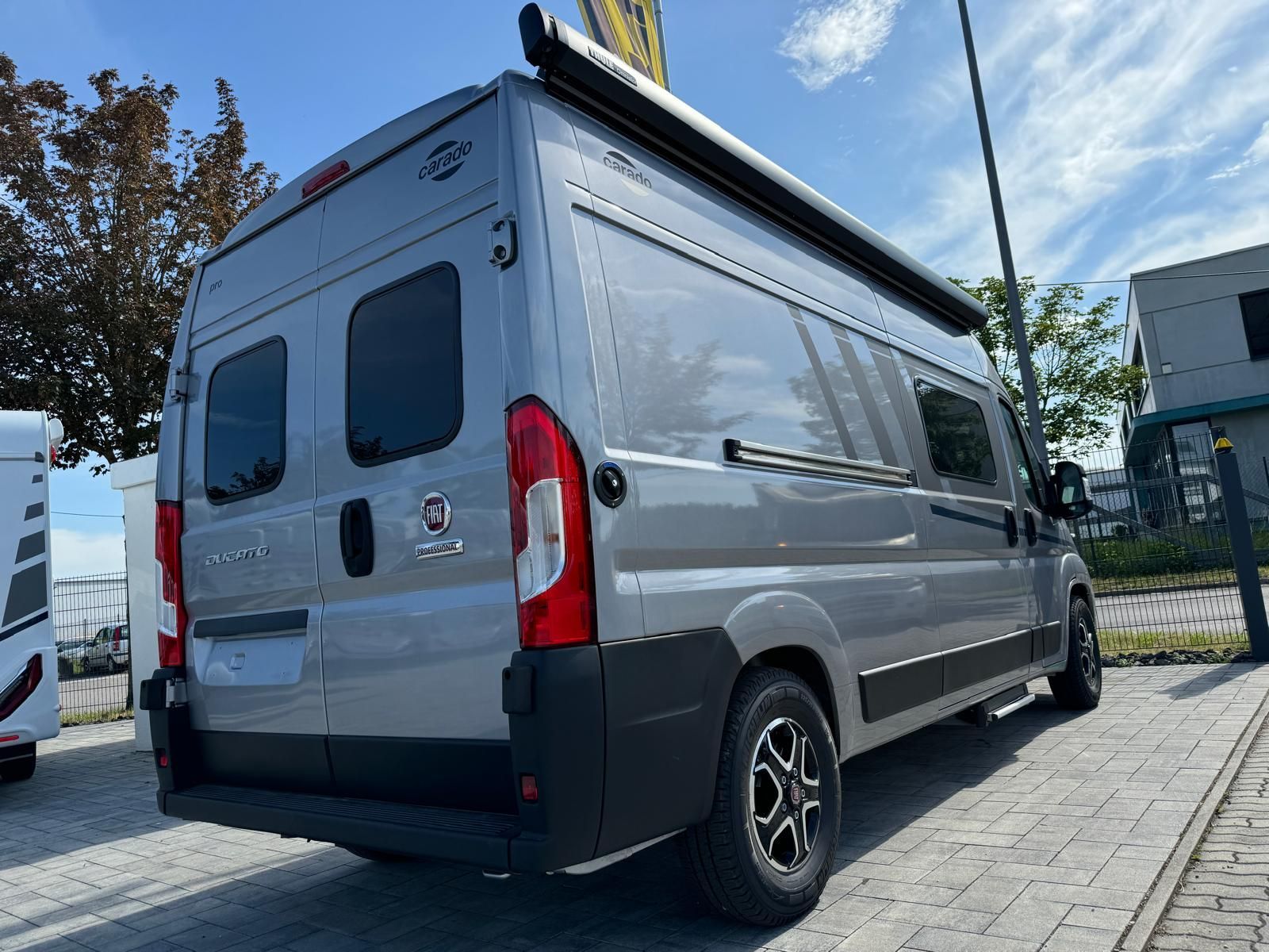 Grauer Wohnwagen mit ausgefahrener Markise steht im Freien.
