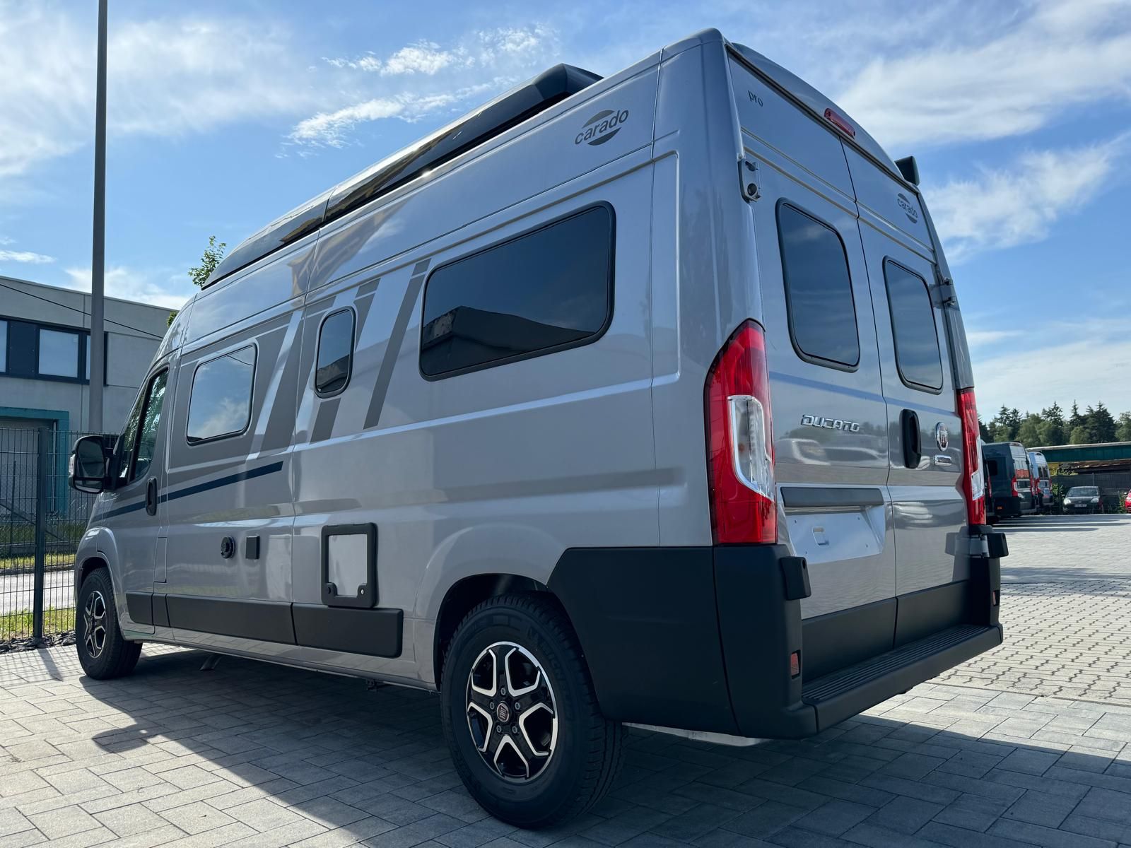 Ein silberner Campervan parkt an einem sonnigen Tag im Freien.