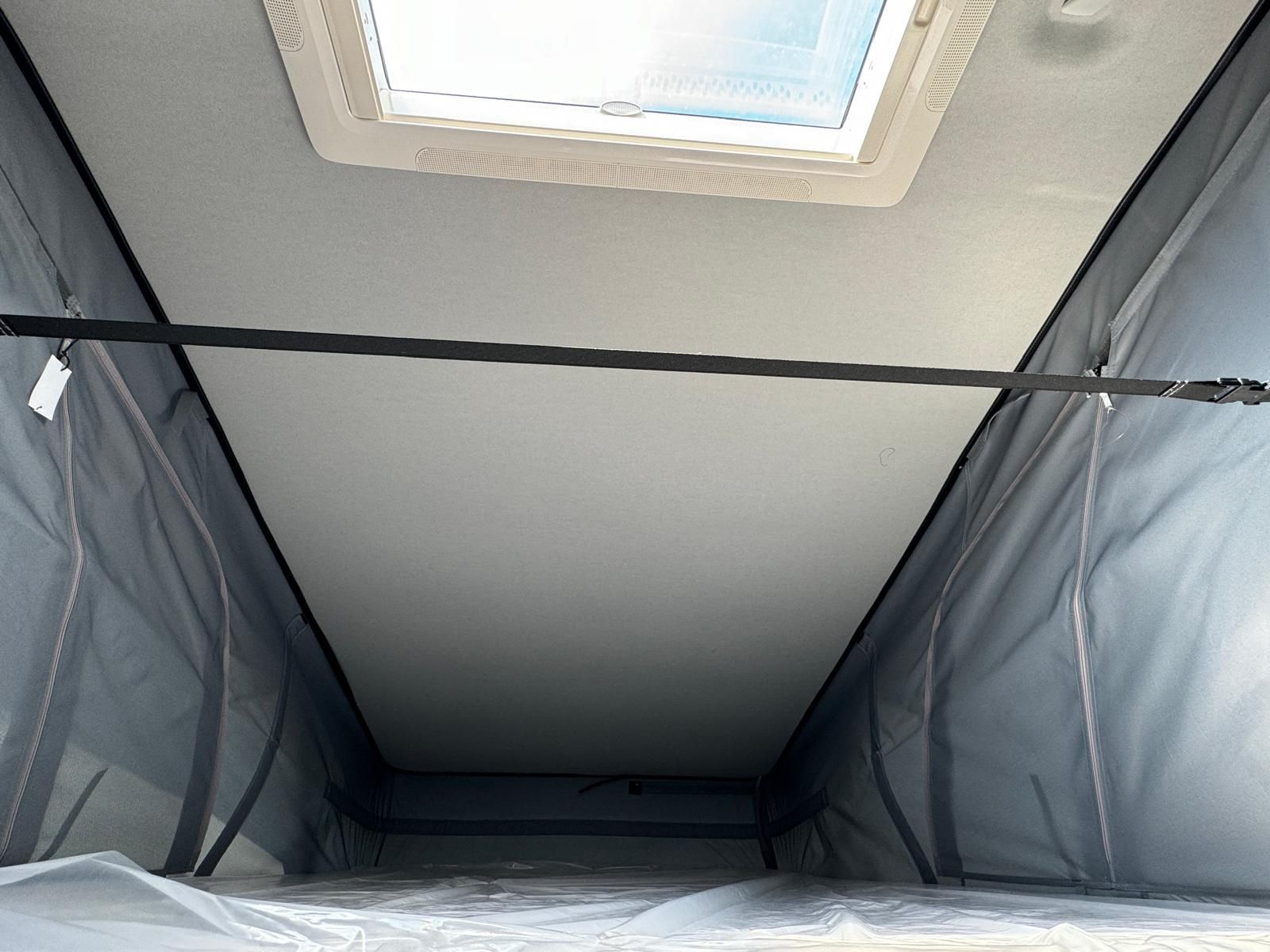 Innenraum eines Wohnmobils mit Hochdach. Dachfenster und Seitenwände aus Netzgewebe sind sichtbar.