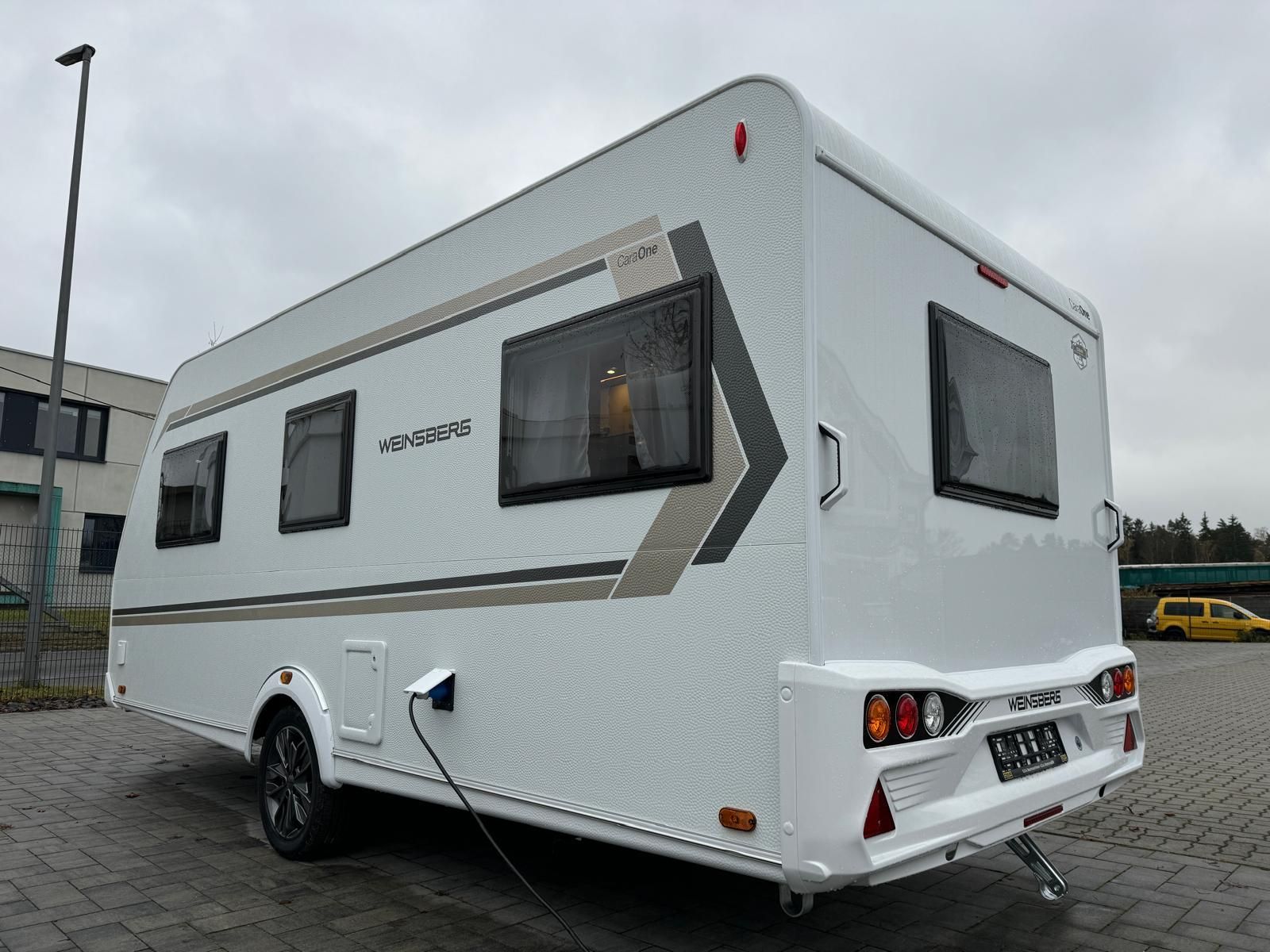 Ein weißer Wohnwagenanhänger steht auf einem Parkplatz.