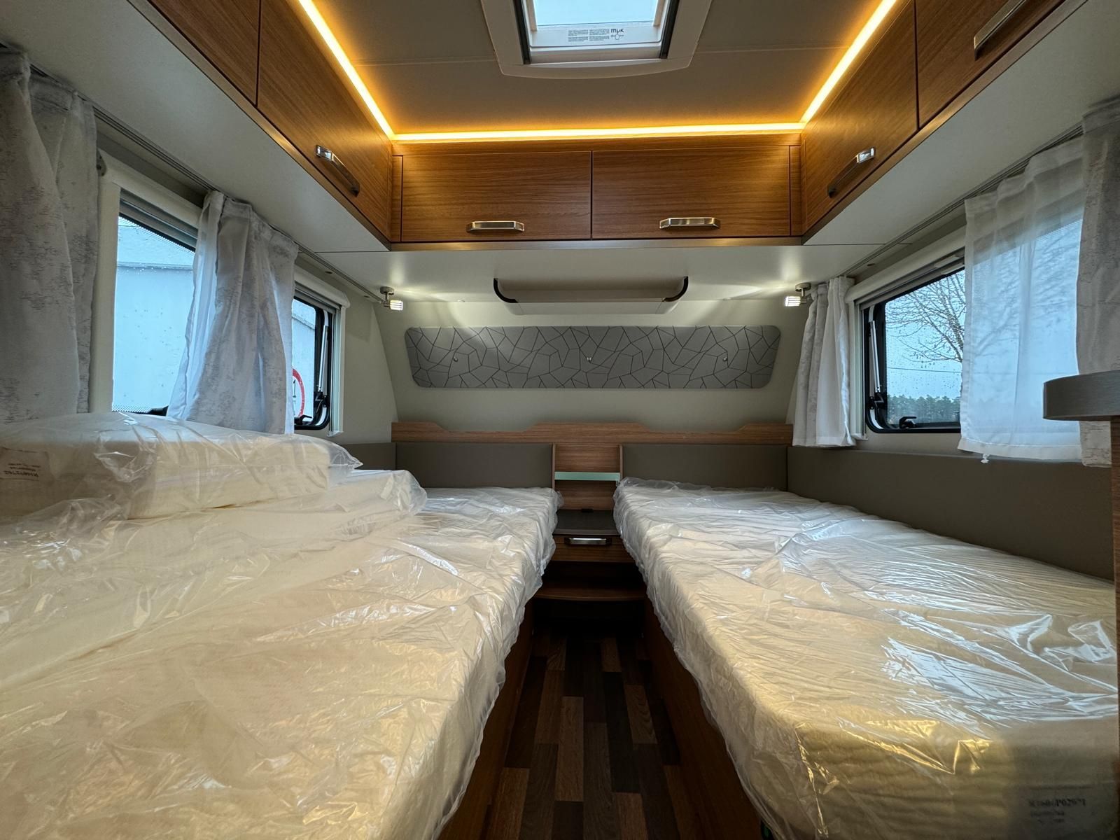 Das Innere eines Wohnmobils mit zwei Betten und einer Deckenleuchte.