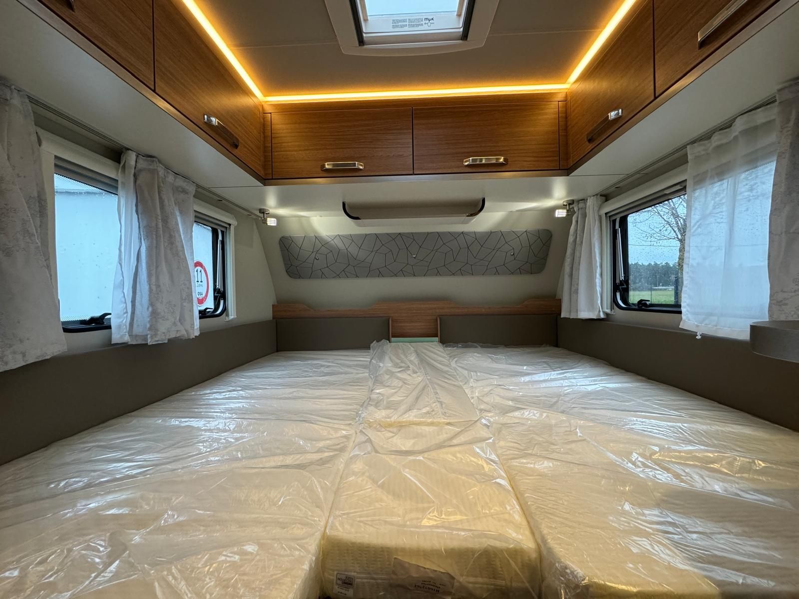 Das Innere eines Wohnmobils mit zwei Betten und einer Deckenleuchte.