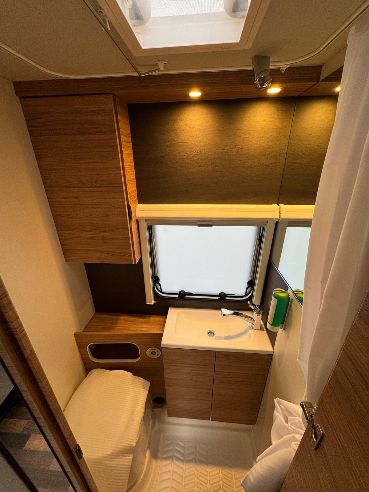 Ein Badezimmer im Wohnmobil mit Toilette, Waschbecken und Duschvorhang.
