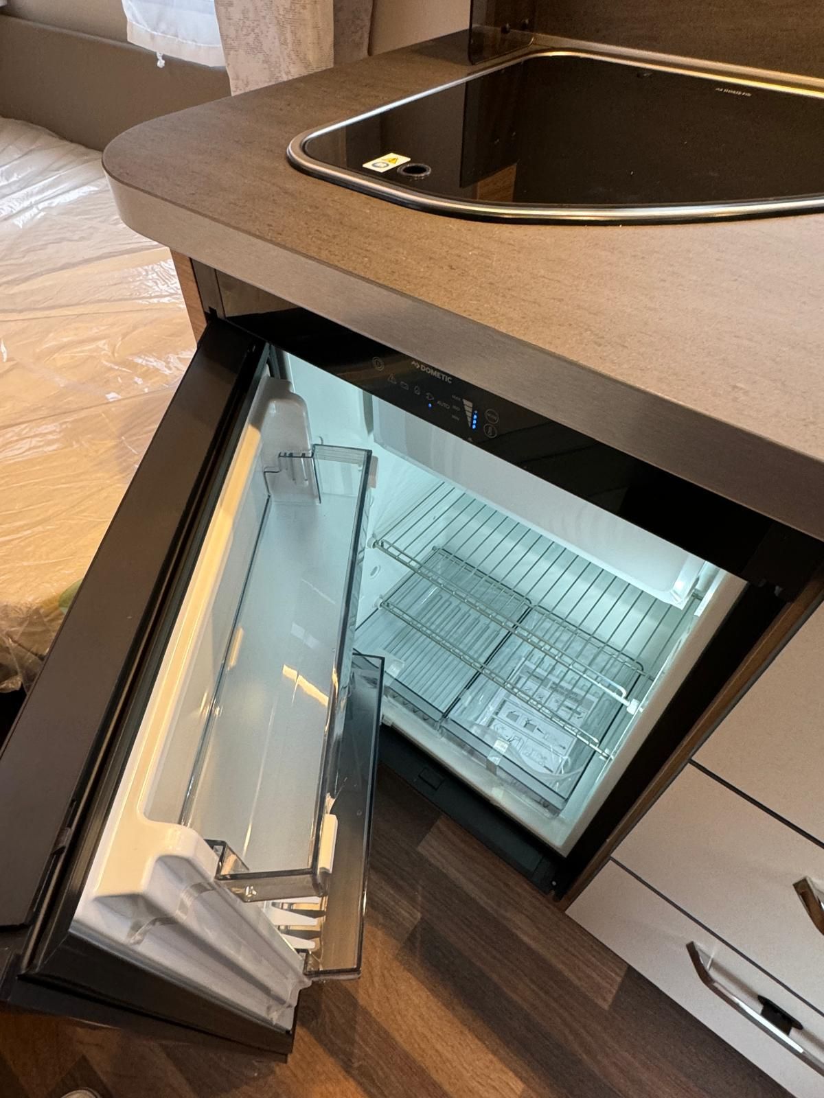 In einer Küche steht neben einer Spüle ein kleiner offener Kühlschrank.