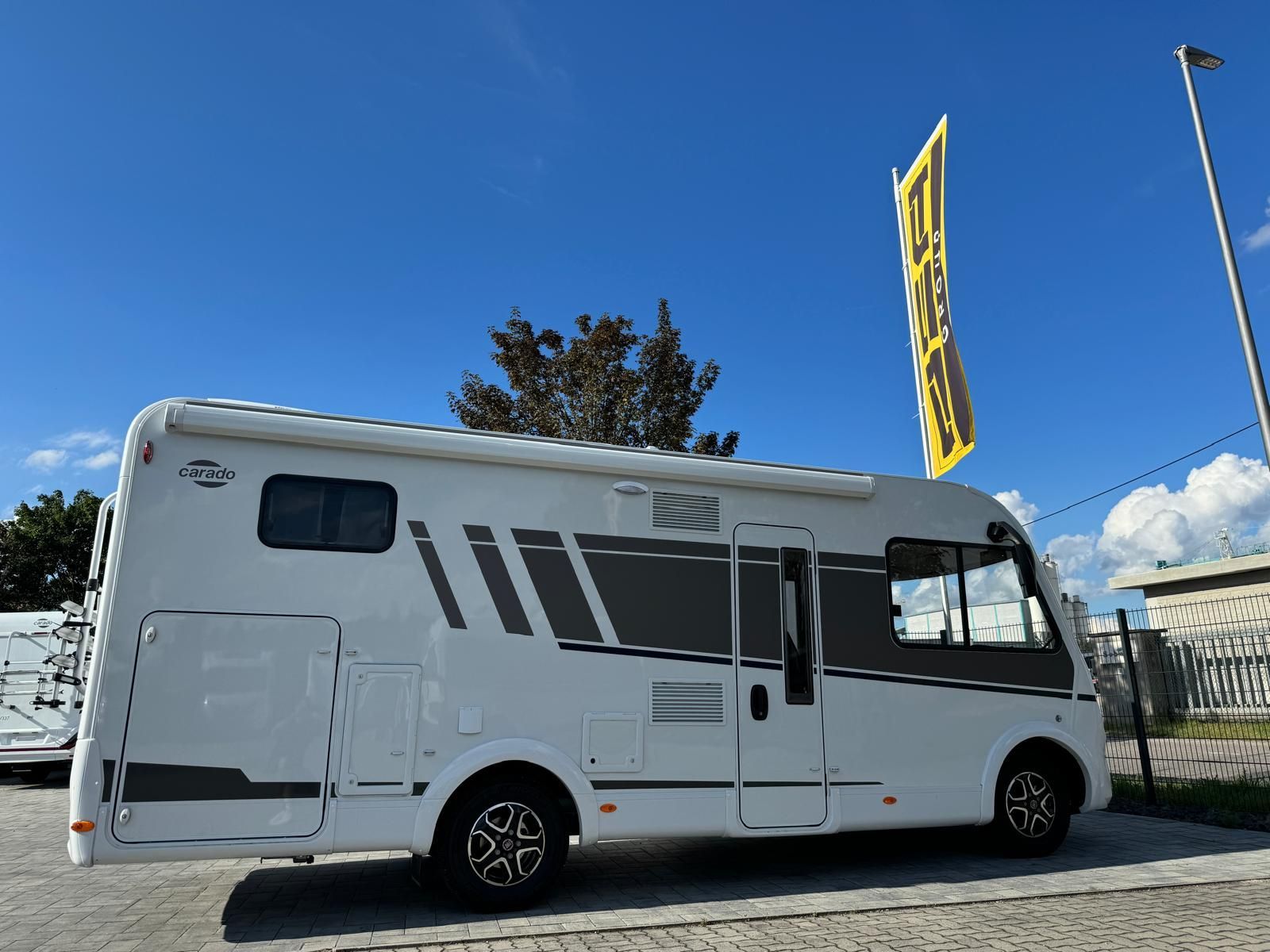 Ein weiß-schwarzes Wohnmobil steht auf einem Parkplatz.