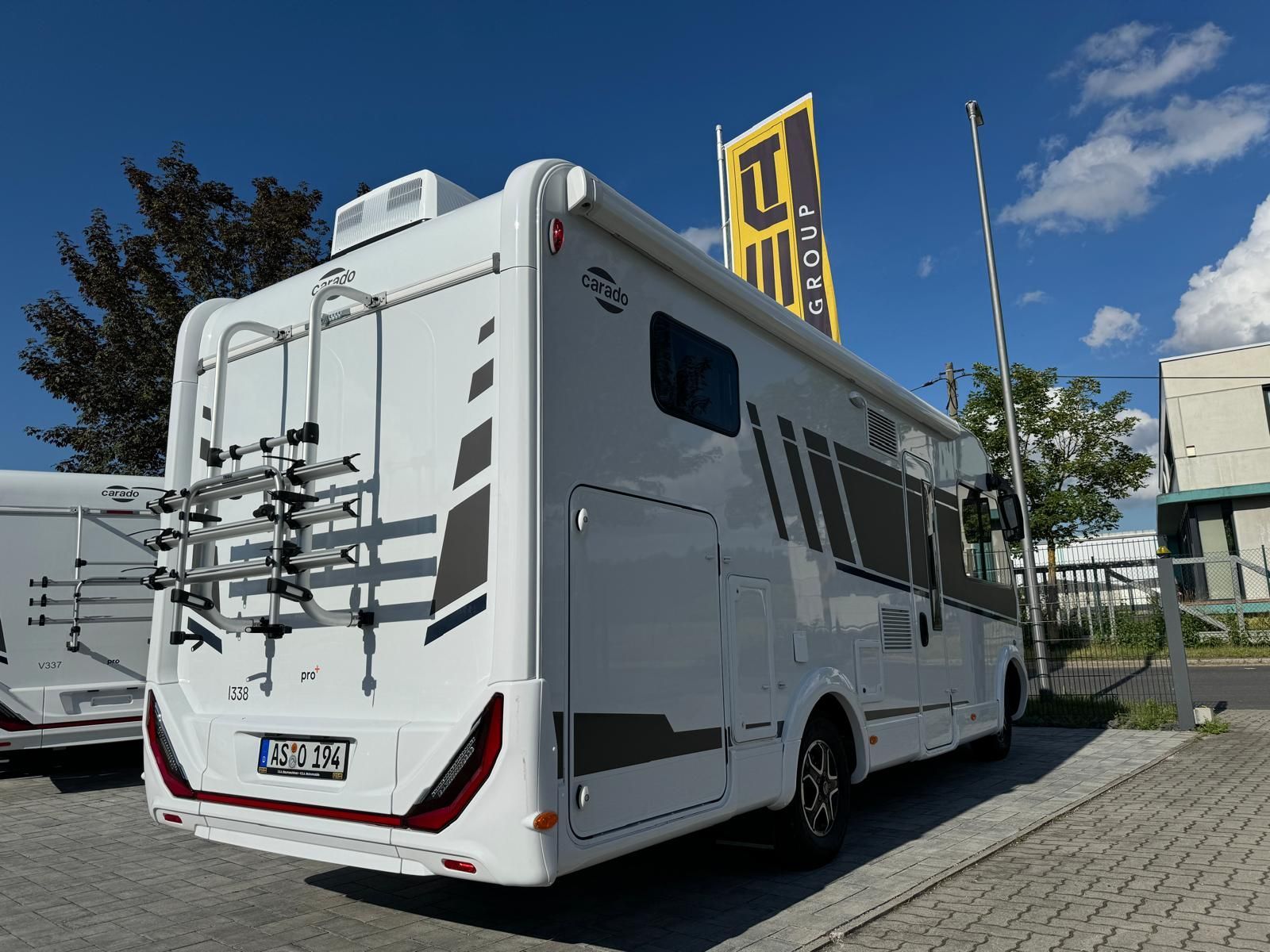 Ein weißes Wohnmobil mit einem Fahrradträger auf der Rückseite steht am Straßenrand.