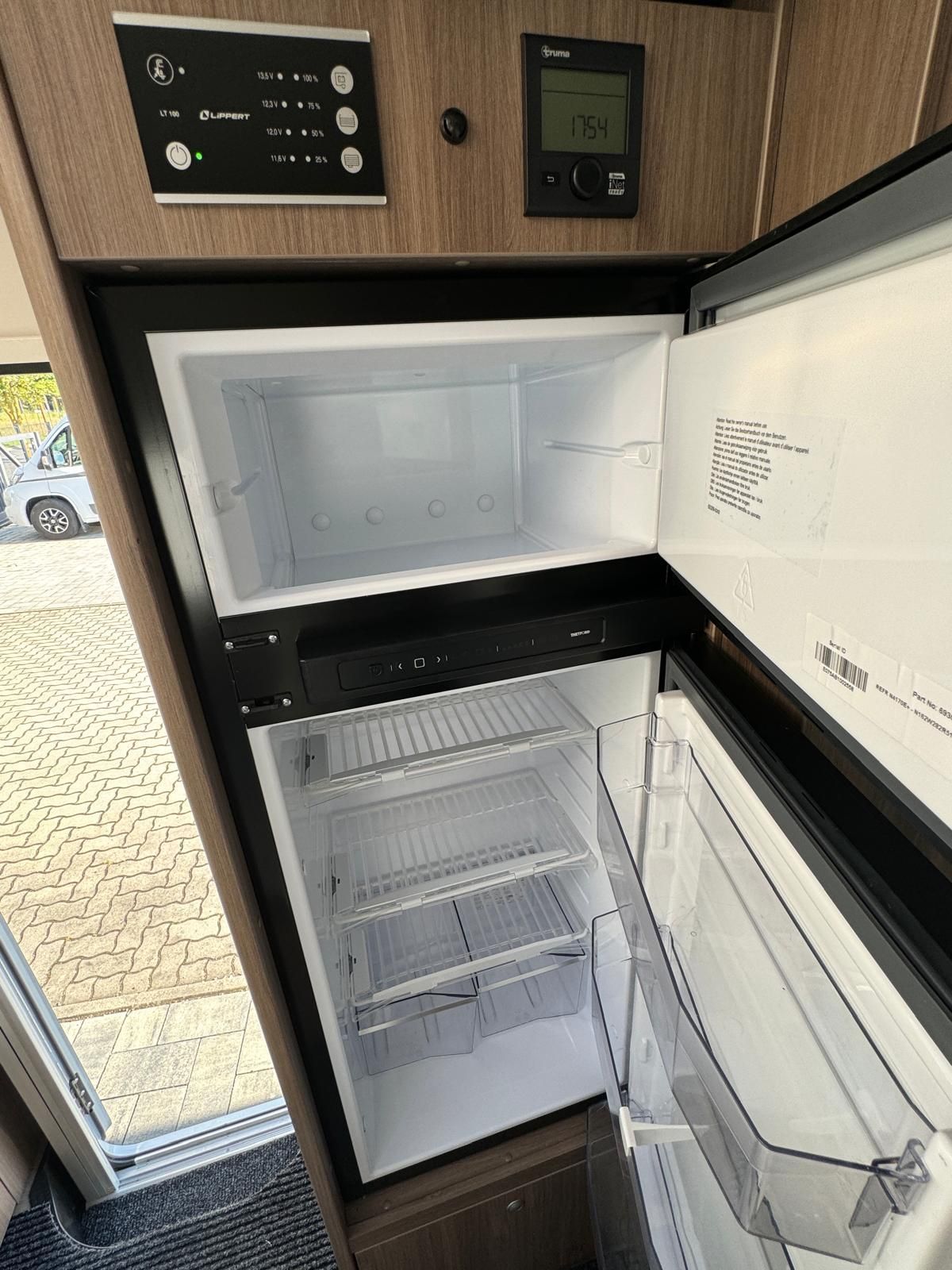 Ein leerer Kühlschrank in einem Wohnmobil mit offener Tür.