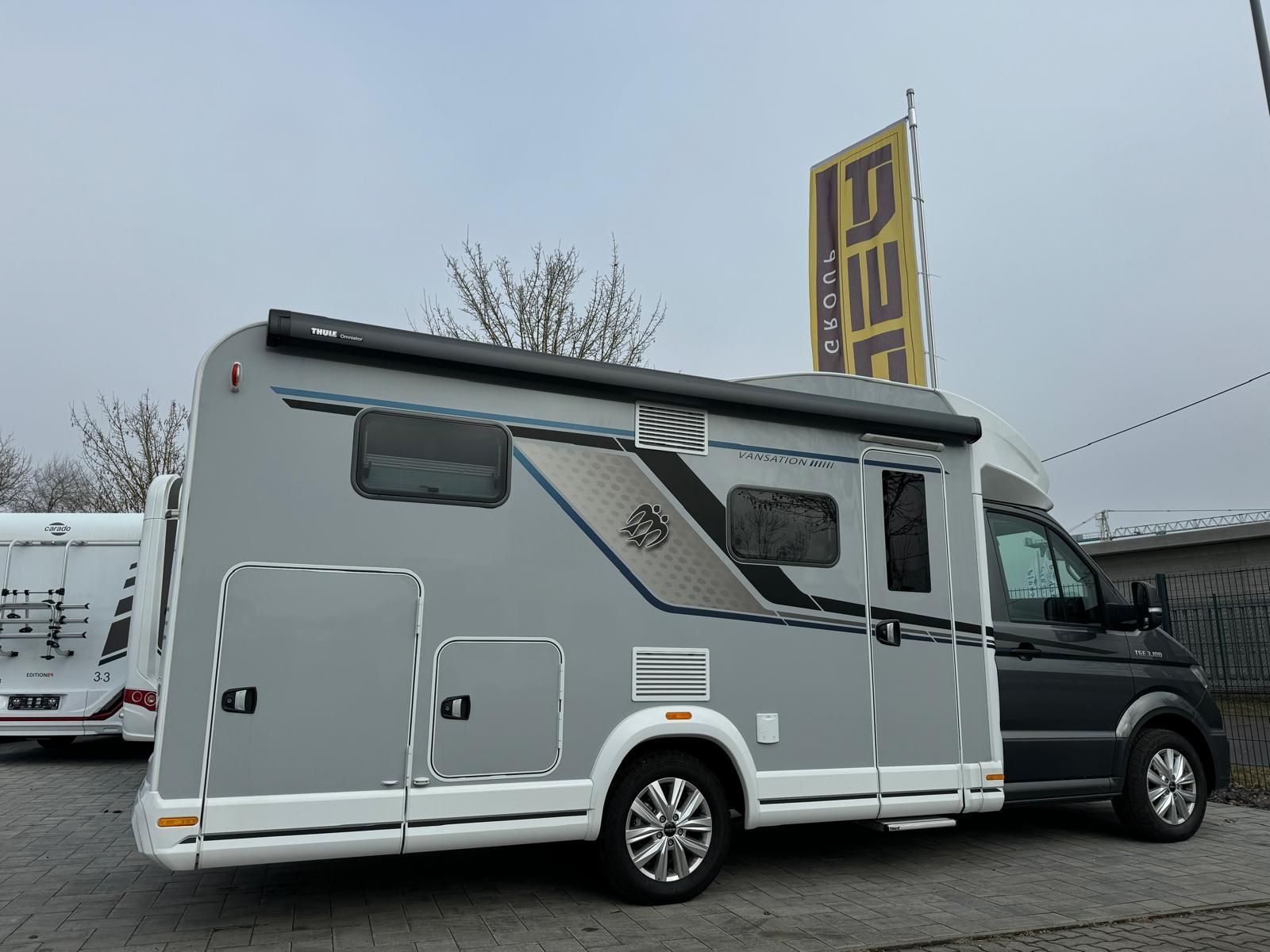 Ein grau-weißes Wohnmobil steht auf einem Parkplatz.