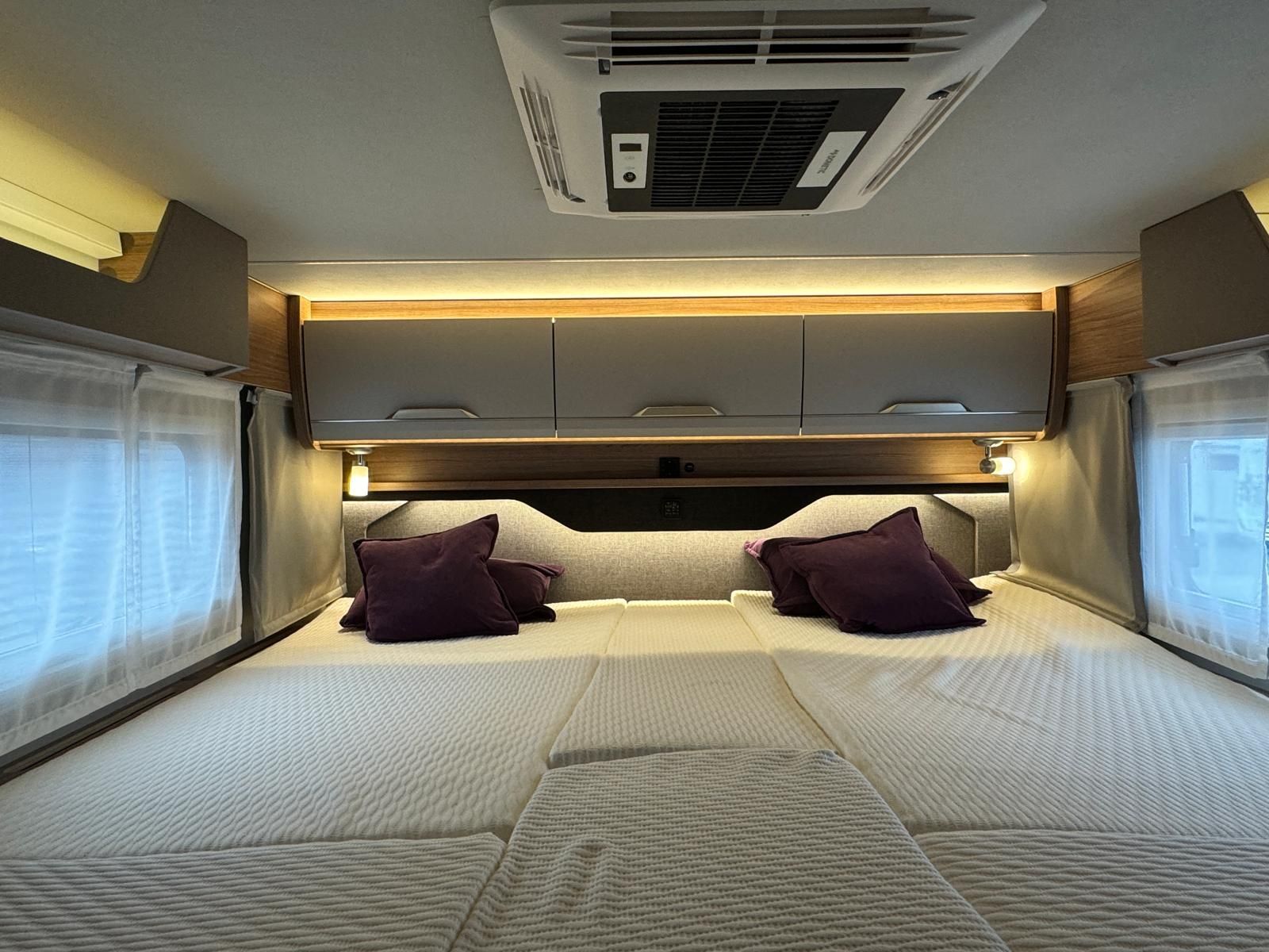 Das Innere eines Wohnmobils mit einem Bett und lila Kissen.