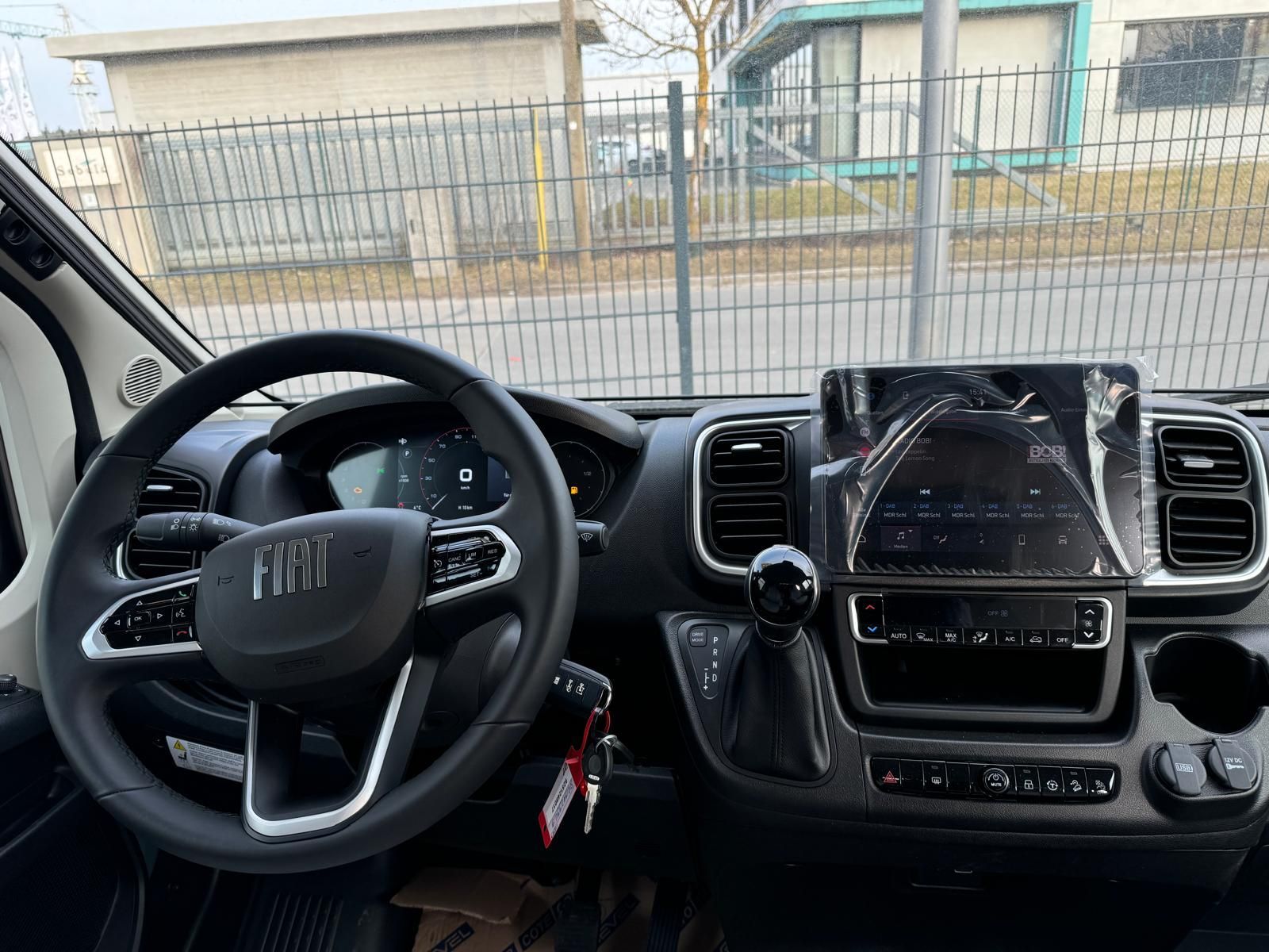 Innenraum eines Fiat-Fahrzeugs, zu sehen sind Lenkrad, Armaturenbrett und Infotainment-Bildschirm.