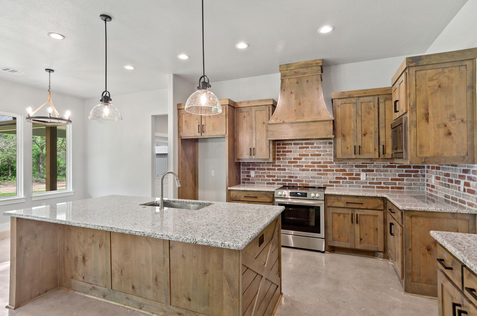 A kitchen with granite countertops, wooden cabinets, and a large island.