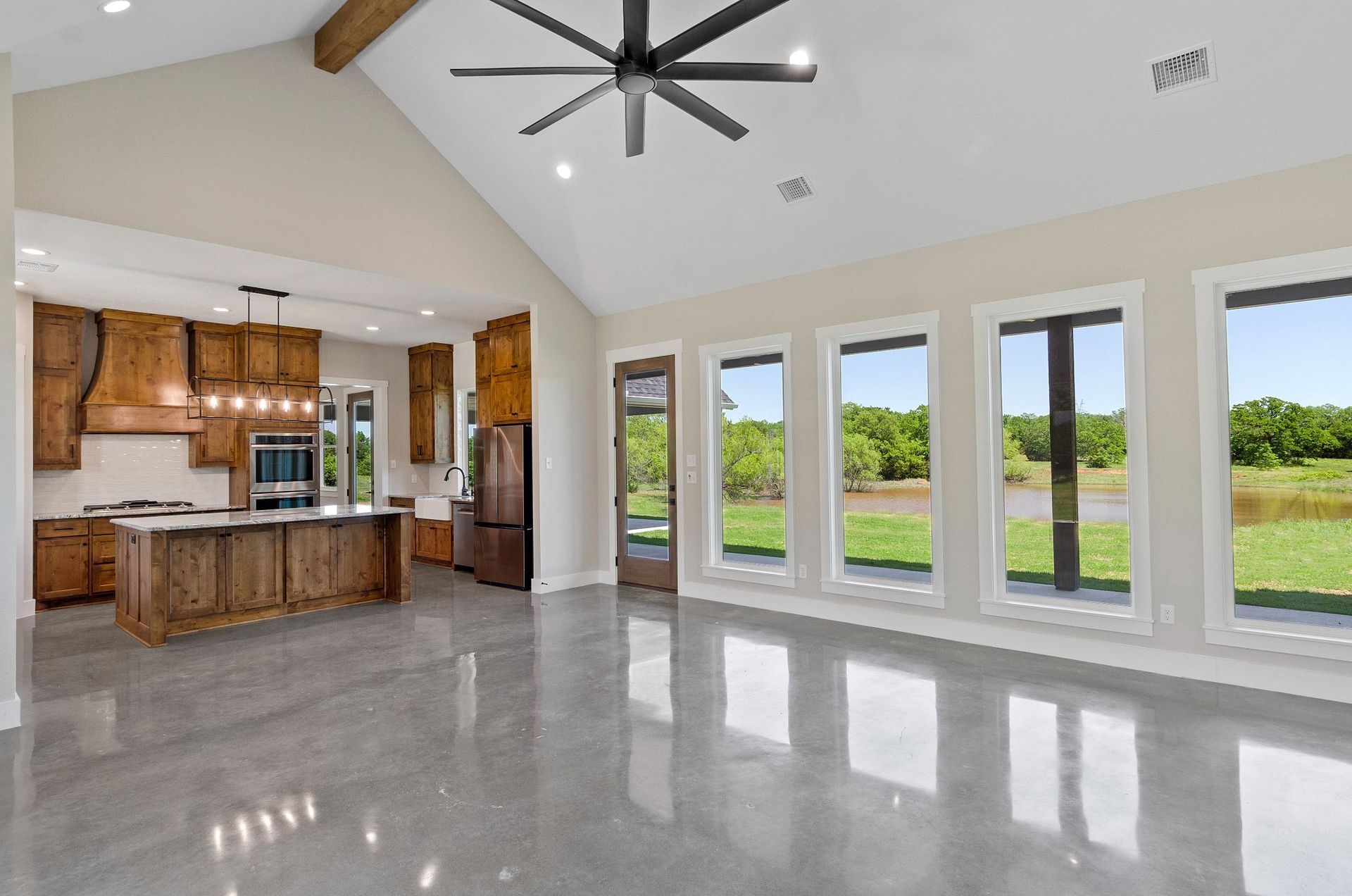 A large empty room with a lot of windows and a ceiling fan.
