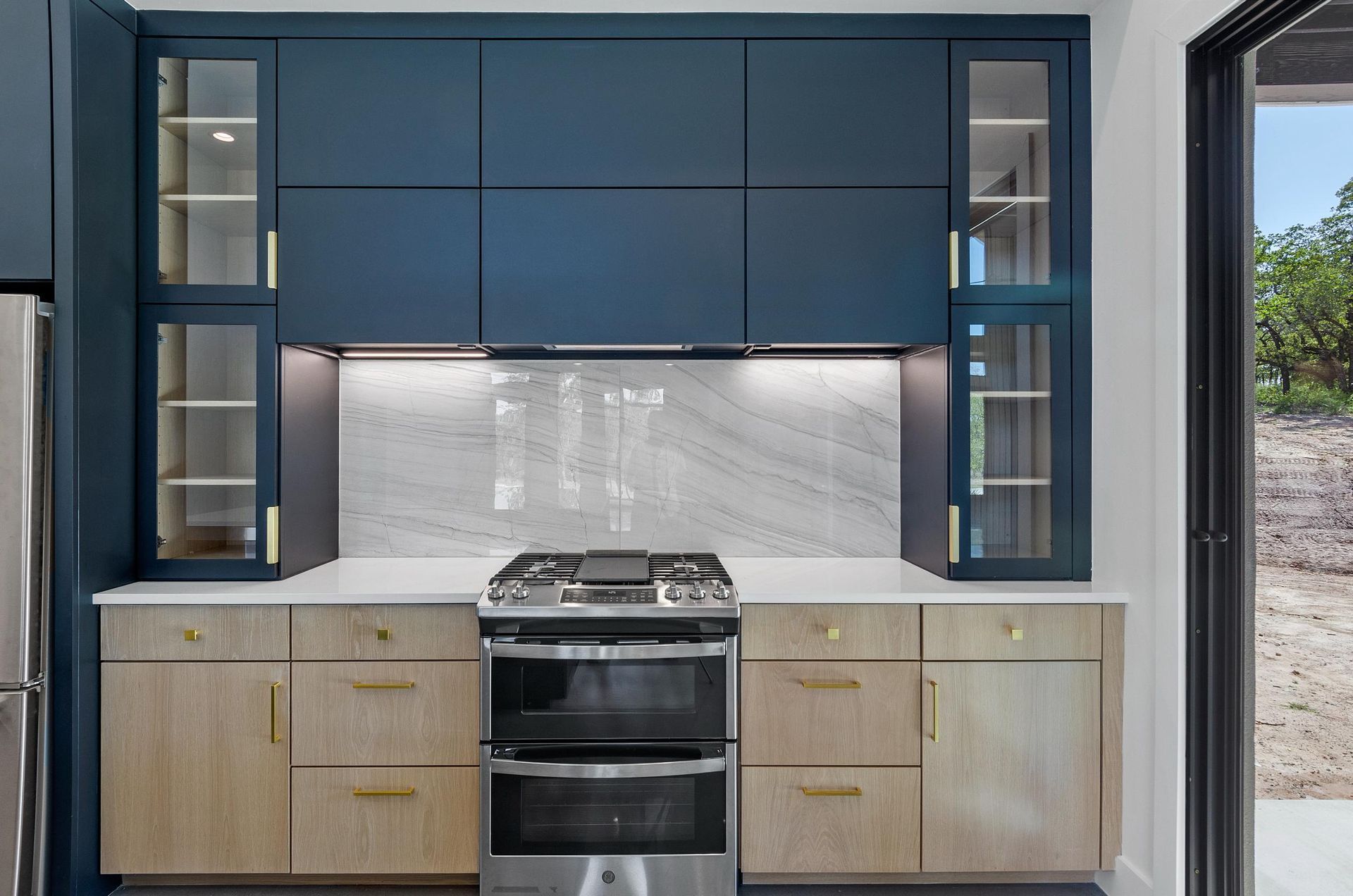 A kitchen with blue cabinets and stainless steel appliances.