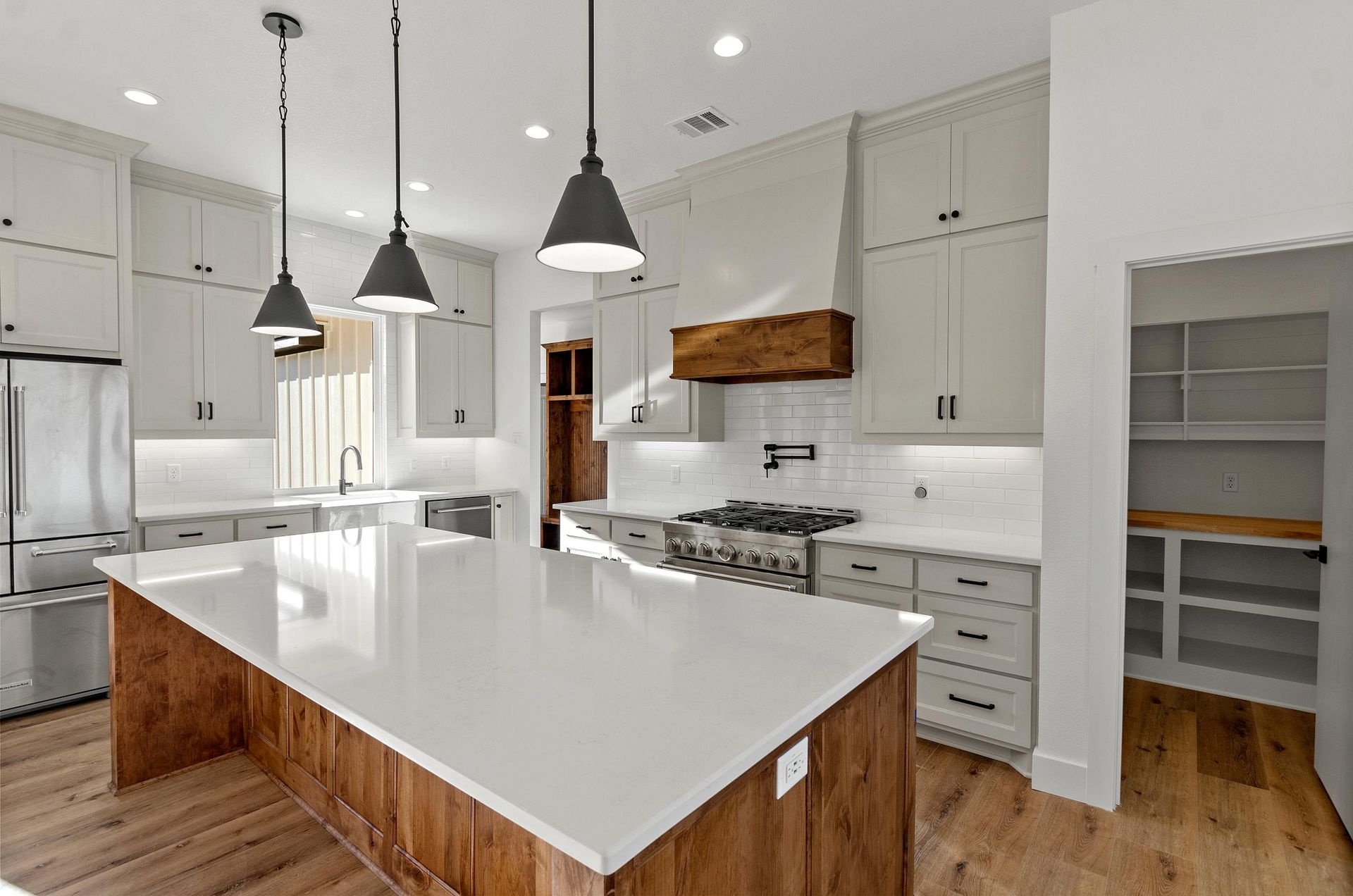 A kitchen with white cabinets and a large island in the middle.