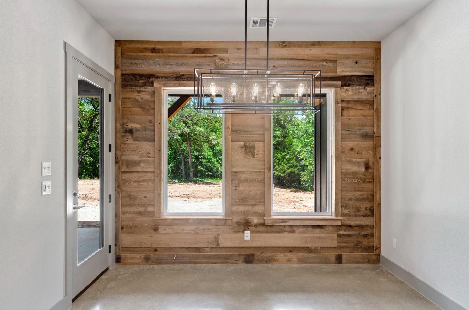 An empty room with a wooden wall and two windows.