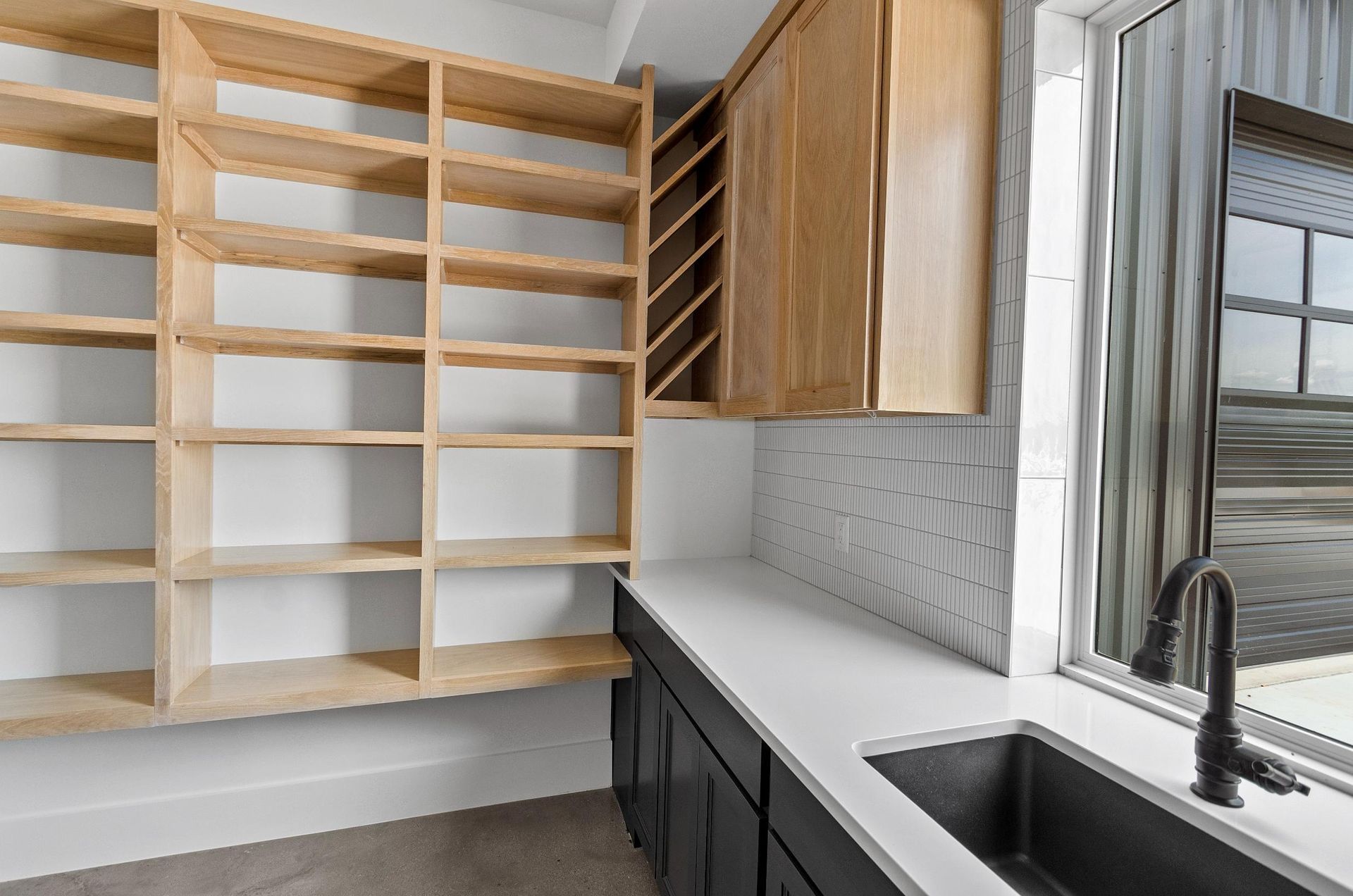 A kitchen with a sink, shelves, and a window.