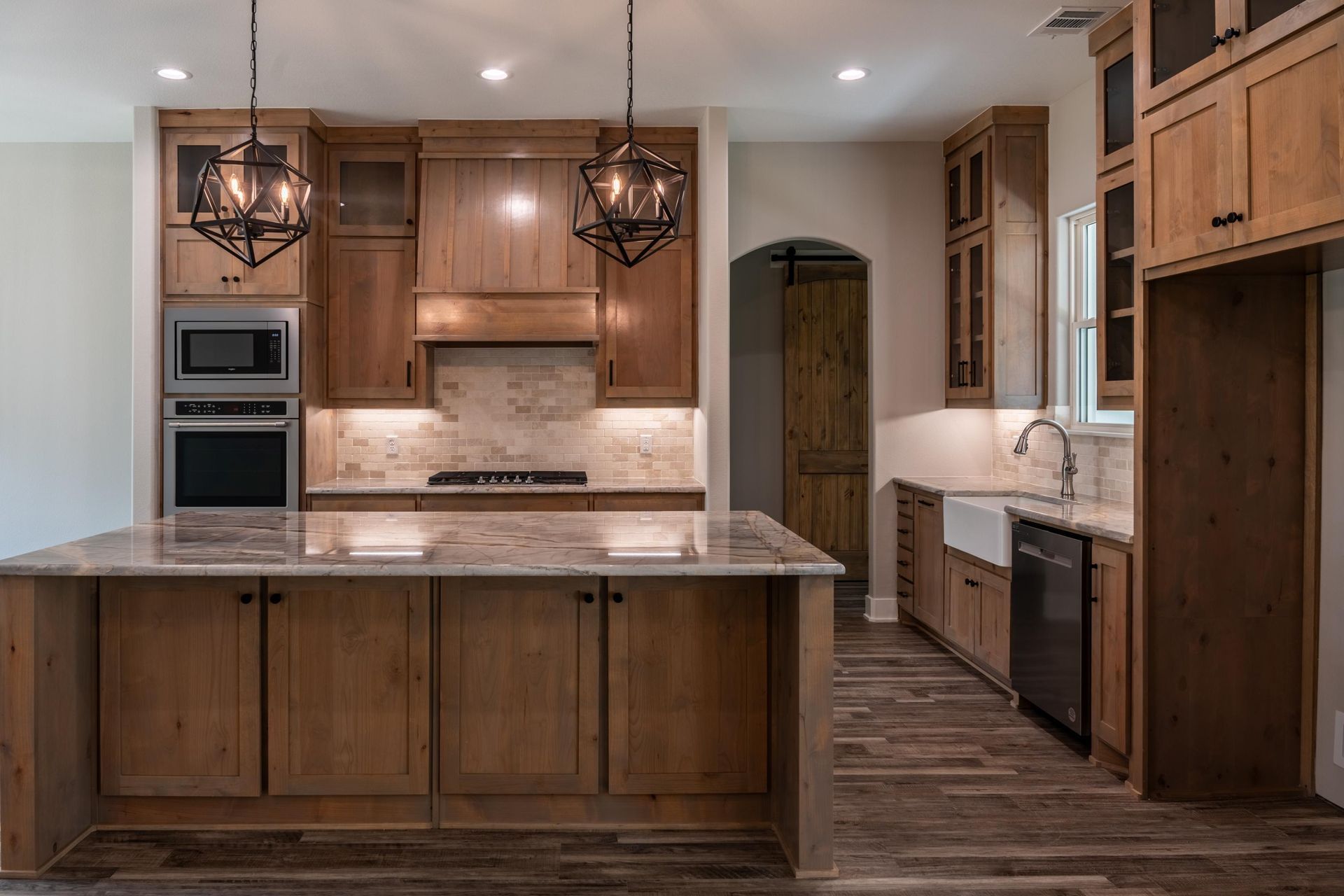 A kitchen with wooden cabinets, granite countertops, and a large island.