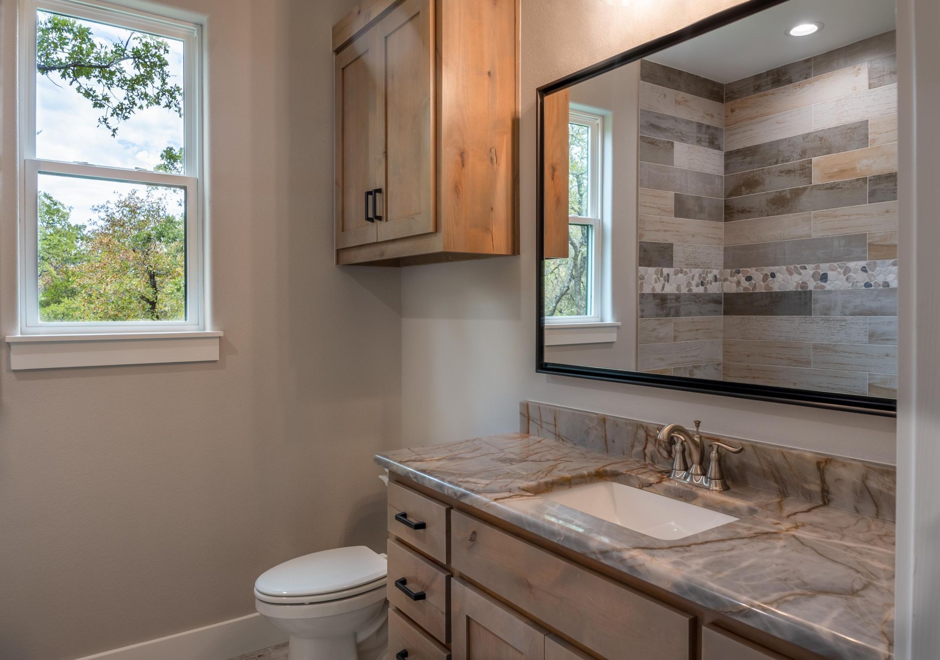 A bathroom with a toilet, sink, and mirror.