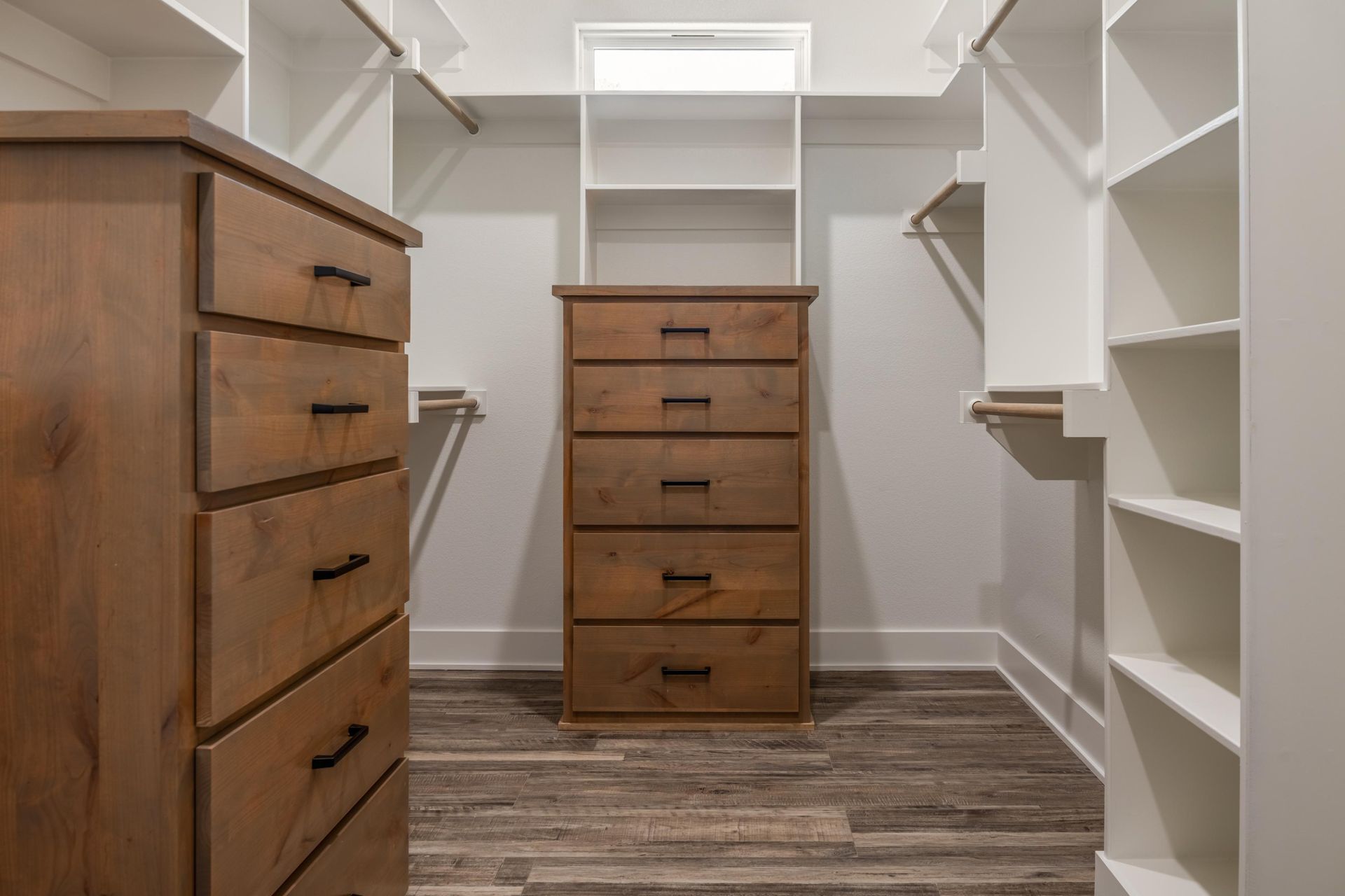 A walk in closet with wooden drawers and shelves.