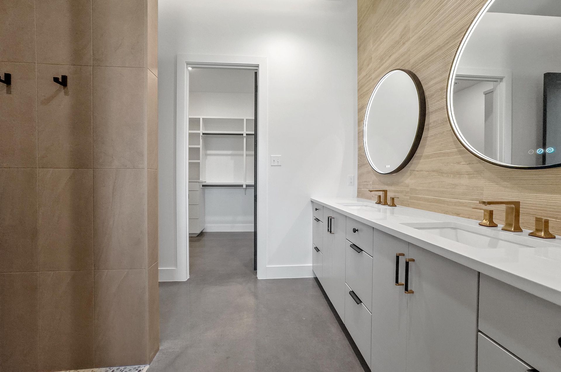 A bathroom with two sinks, two mirrors, and a walk-in closet.