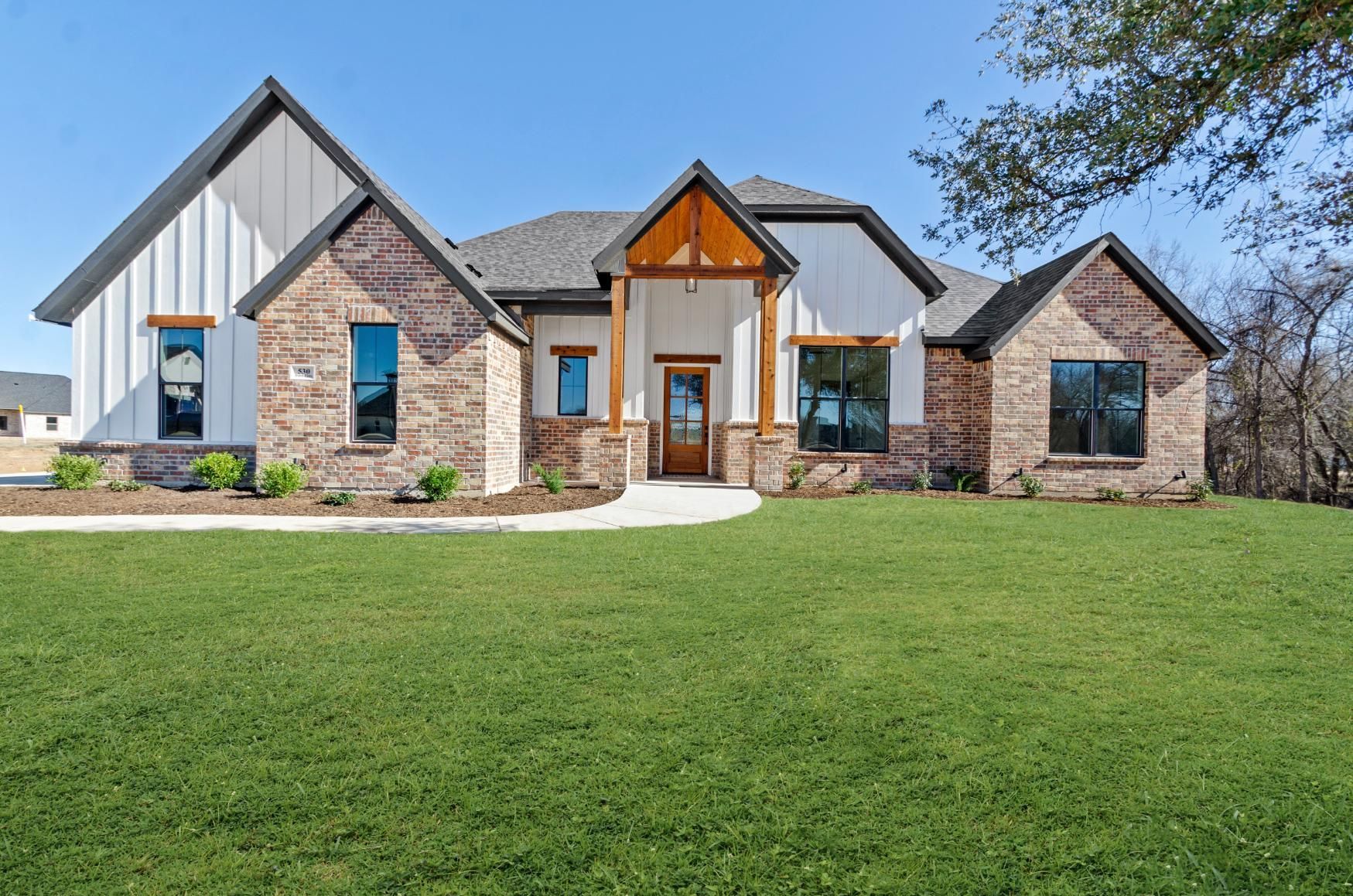 A large house with a lot of windows is sitting on top of a lush green field.