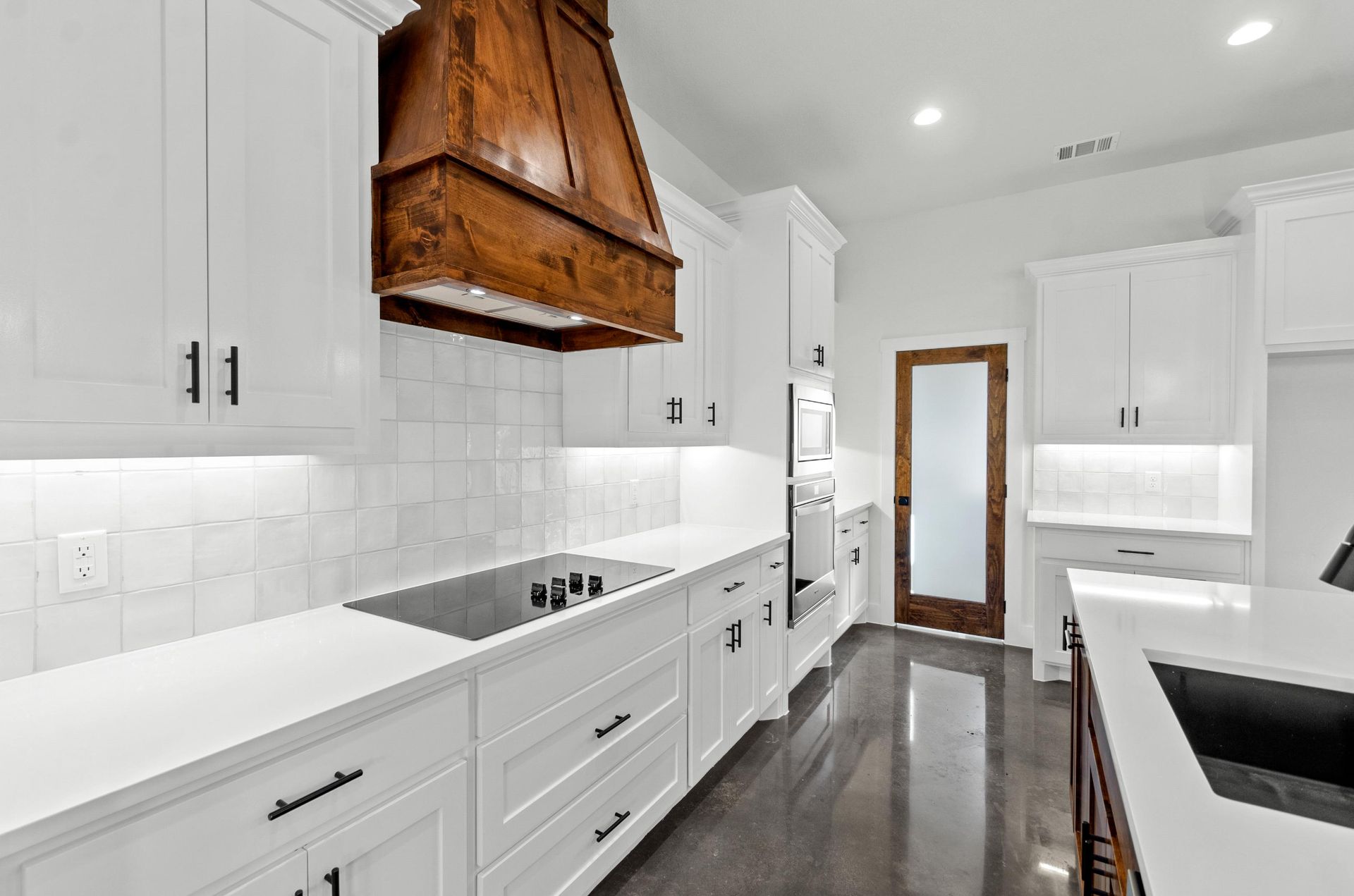 A kitchen with white cabinets and a copper hood.