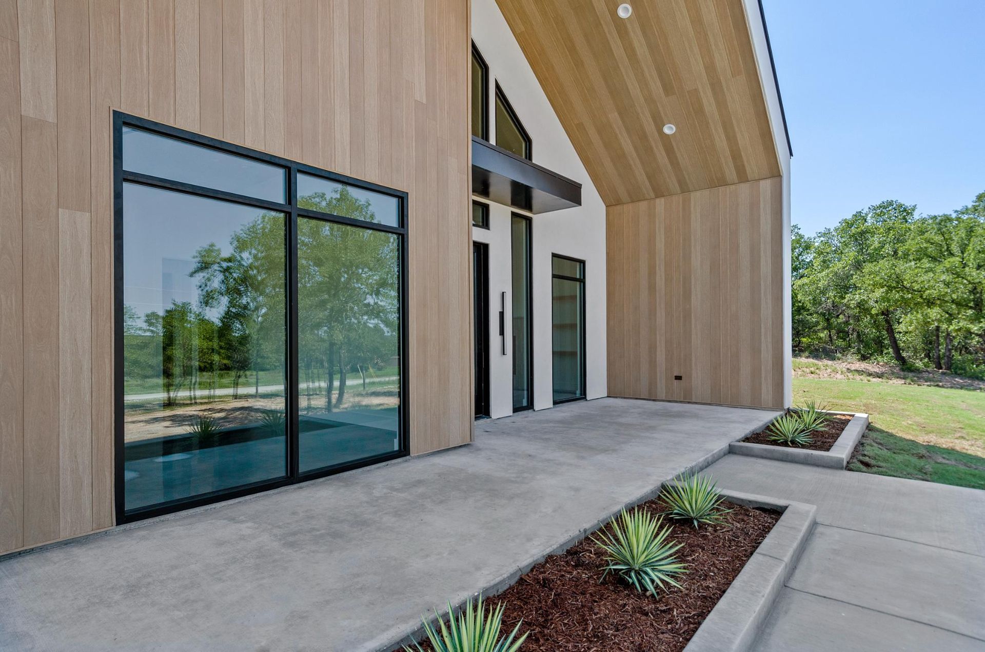 A modern house with a concrete walkway leading to the front door.